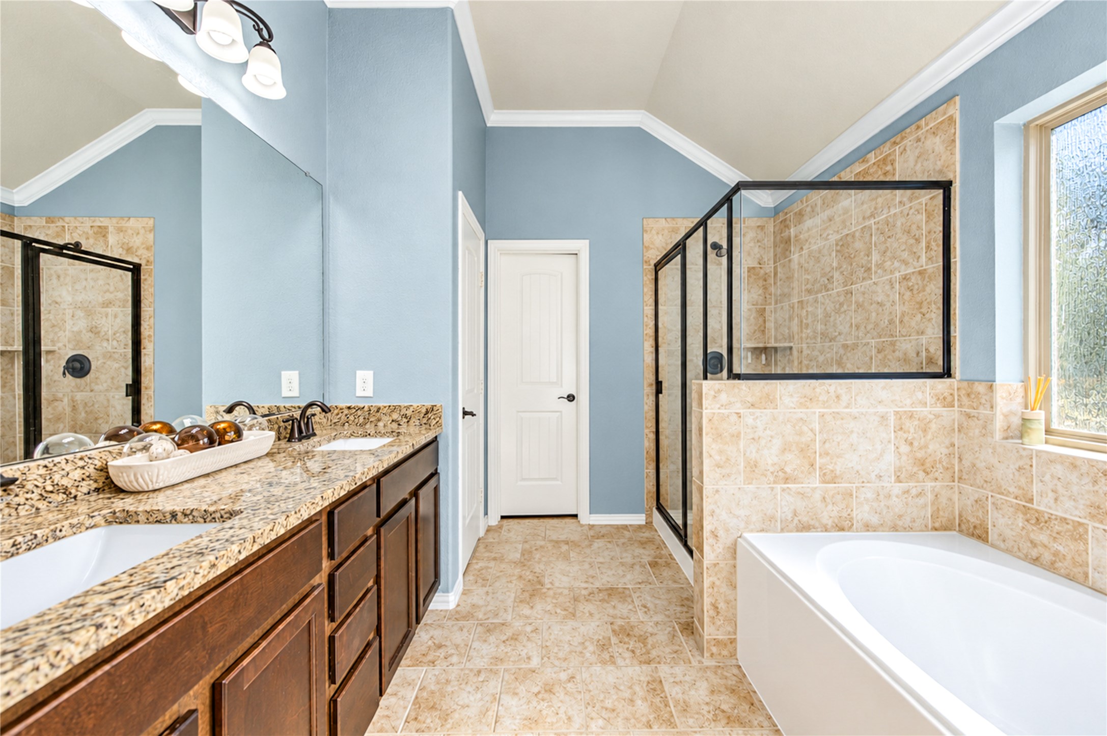 The primary bath pairs a granite vanity with a separate tiled walk-in shower and a soaking tub.