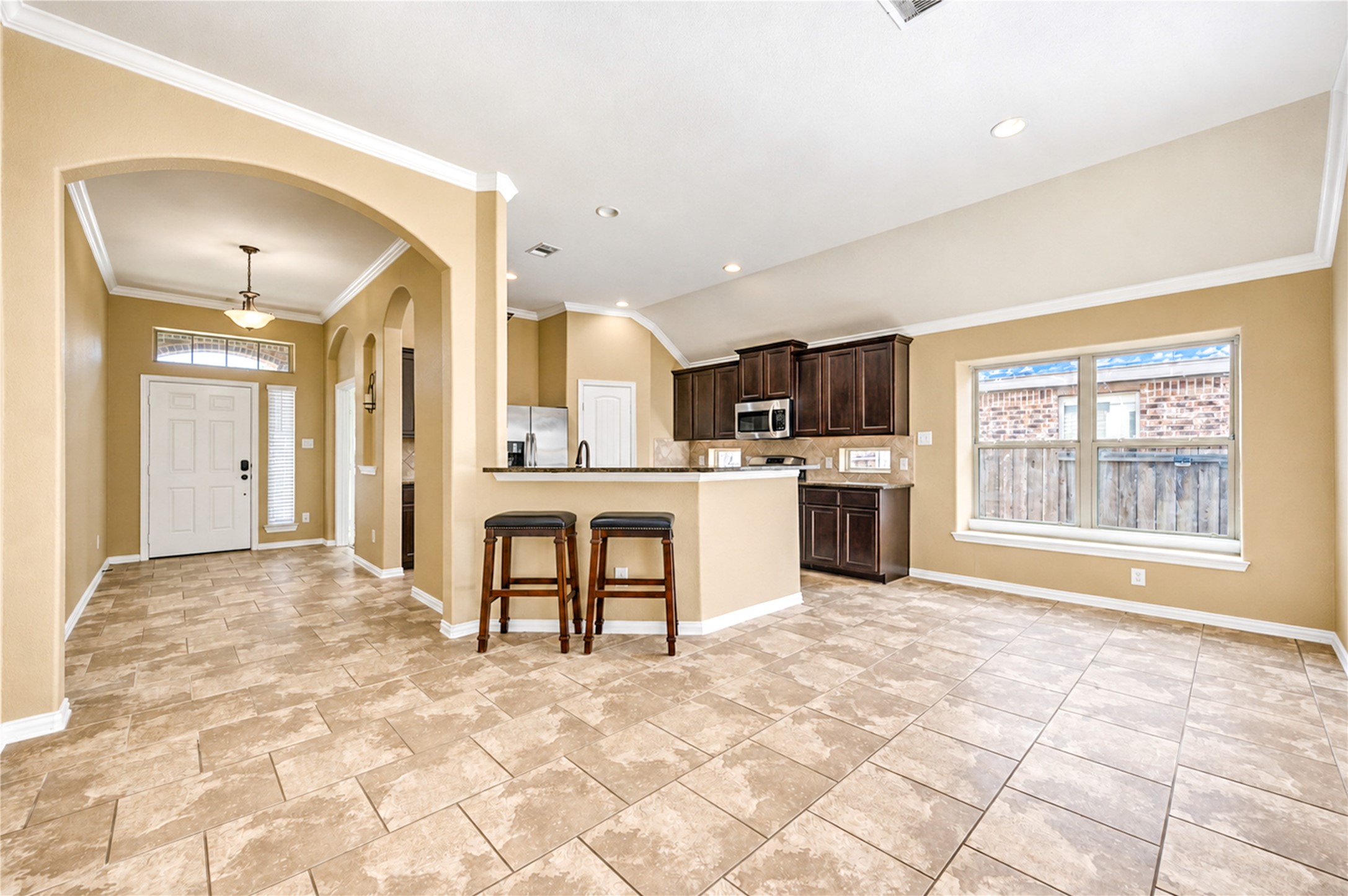 From the foyer, a graceful arch opens to the kitchen, where the breakfast bar anchors the shared living space.