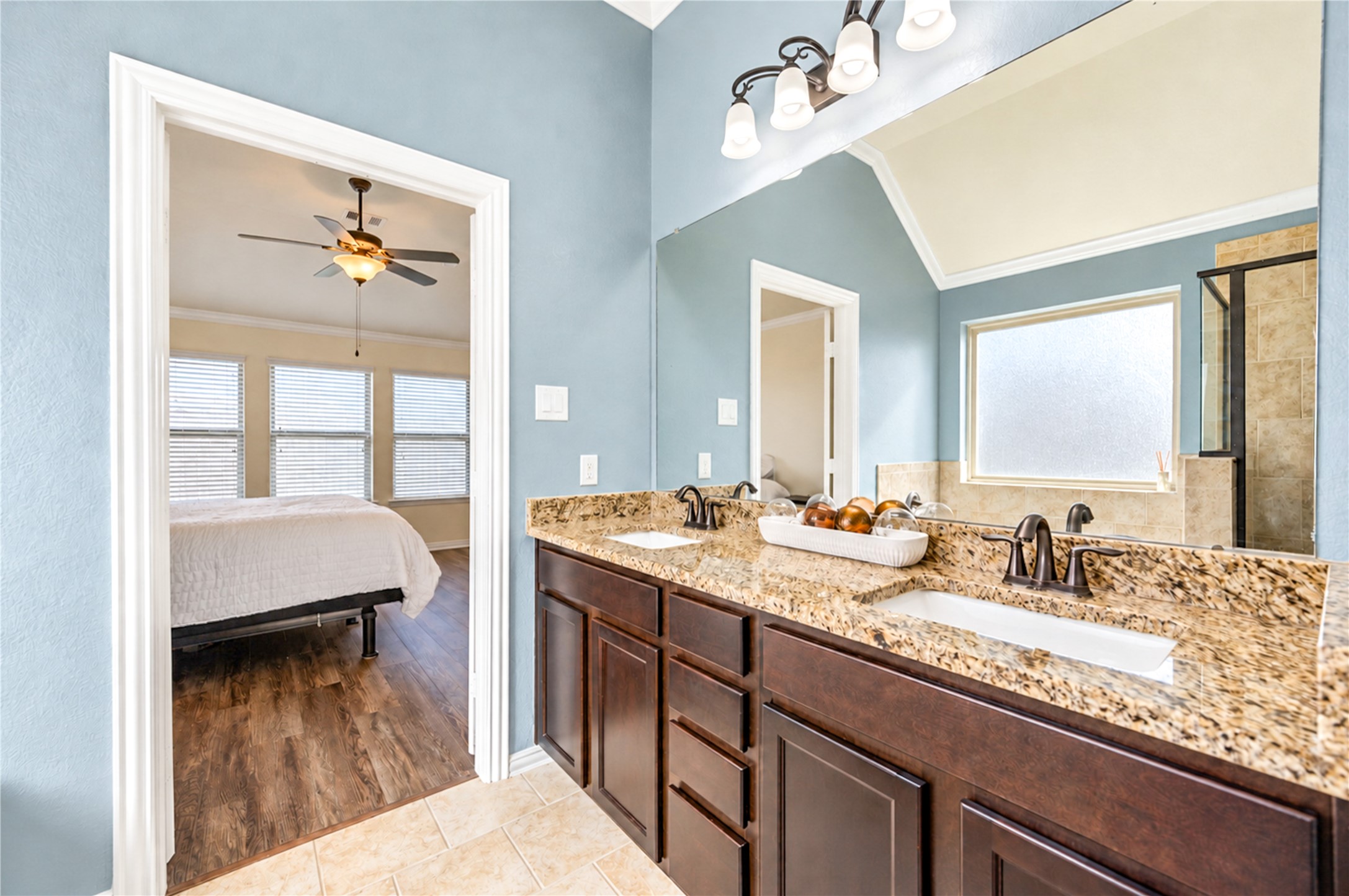 The primary bath's granite vanity with dual sinks opens directly to the bedroom.