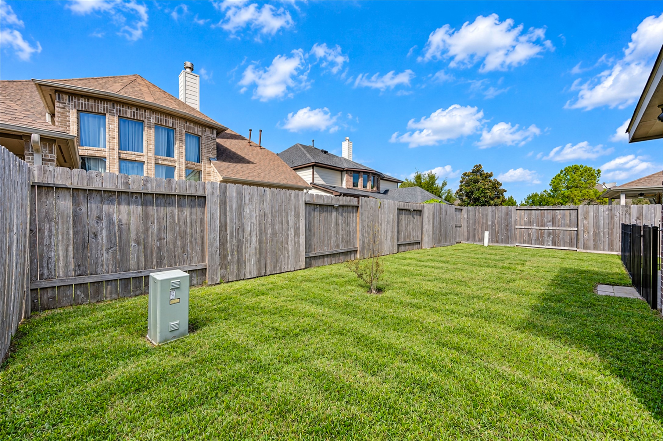 A wood privacy fence surrounds the open backyard, with room to garden or add a pool.