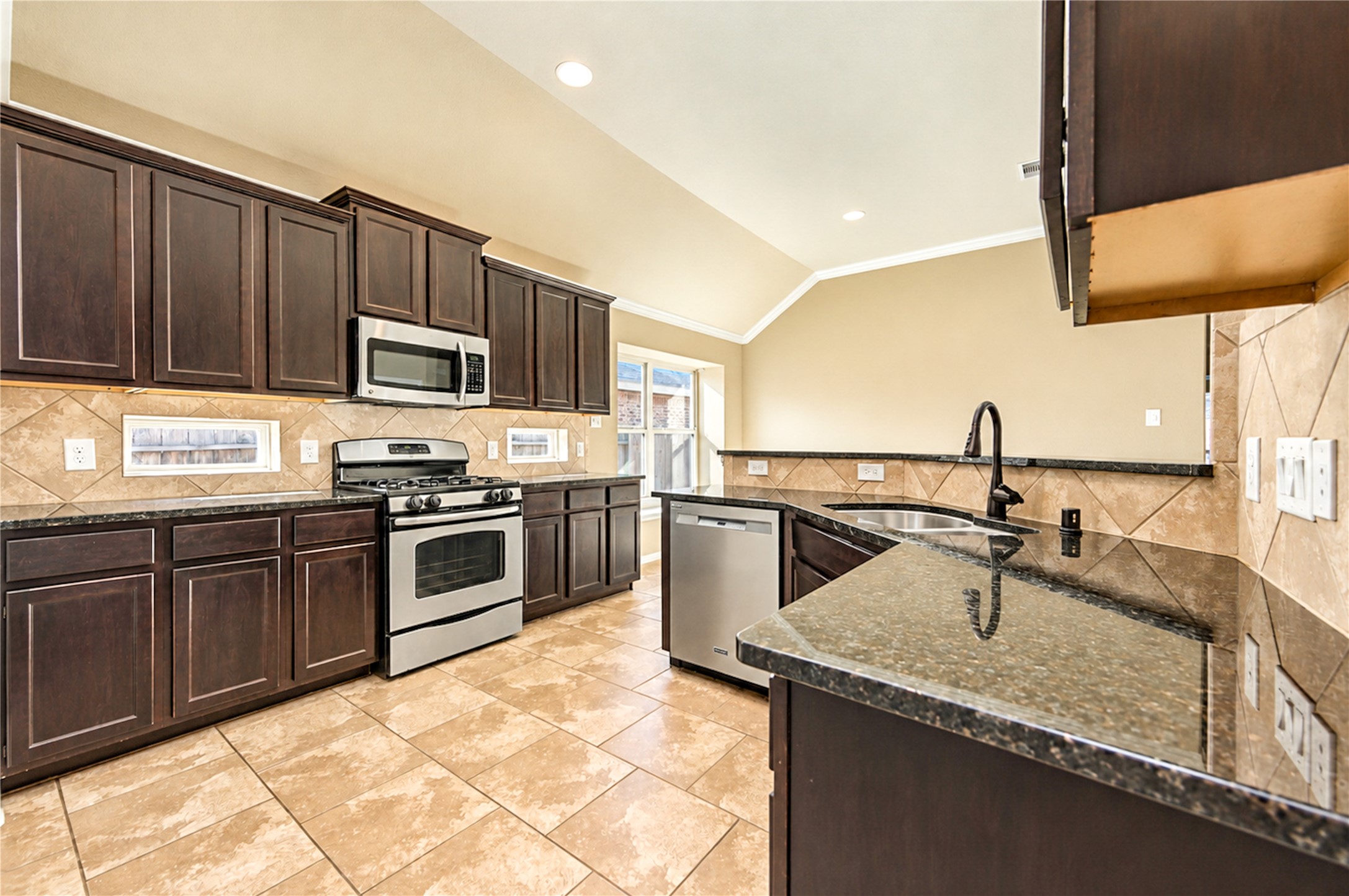 Warm cabinetry, a tile backsplash and a vaulted ceiling give the kitchen an inviting, well-organized layout.