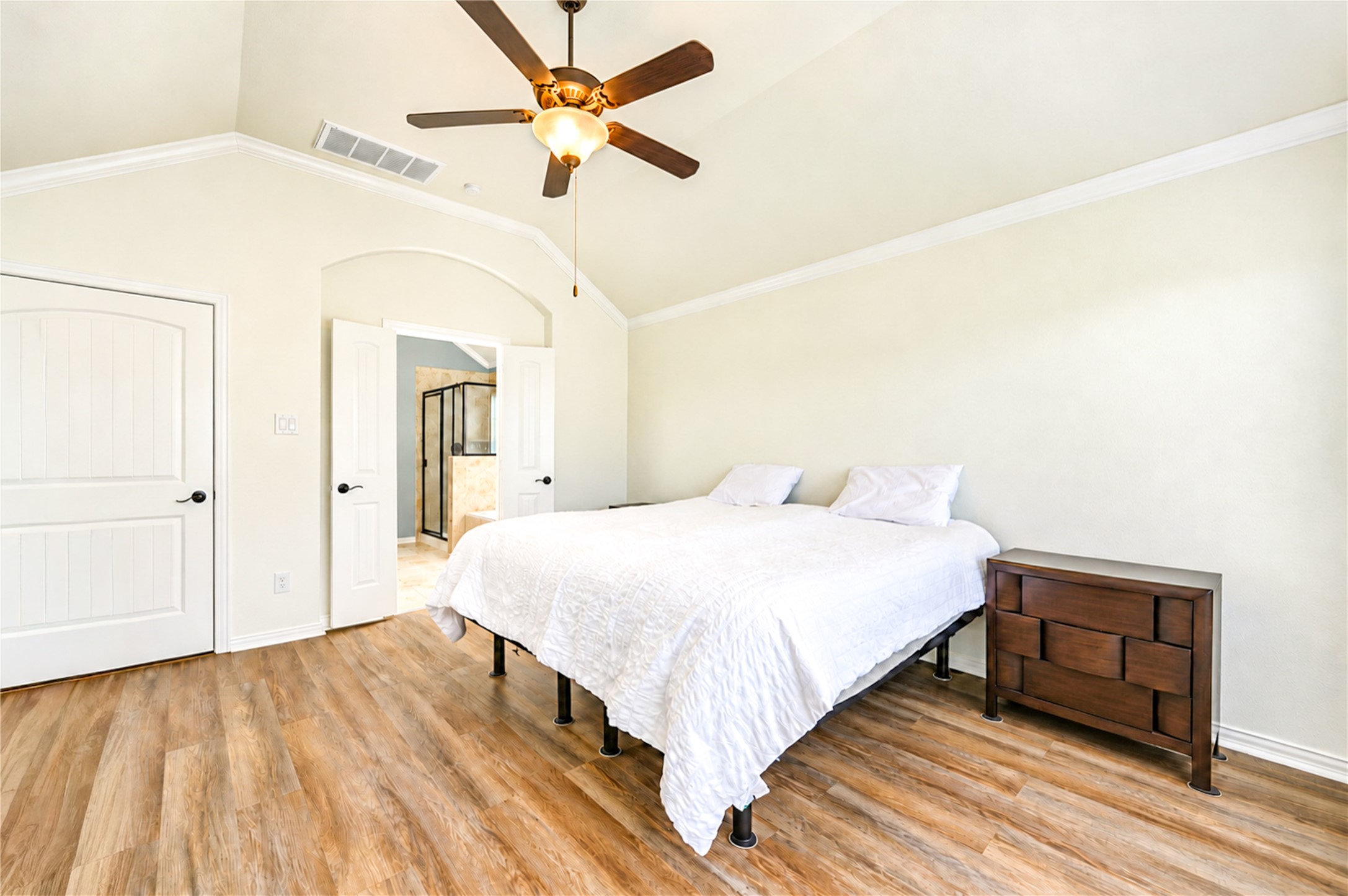 A tall ceiling and luxury vinyl plank flooring make the primary bedroom a calm retreat, with the bath entry nearby.