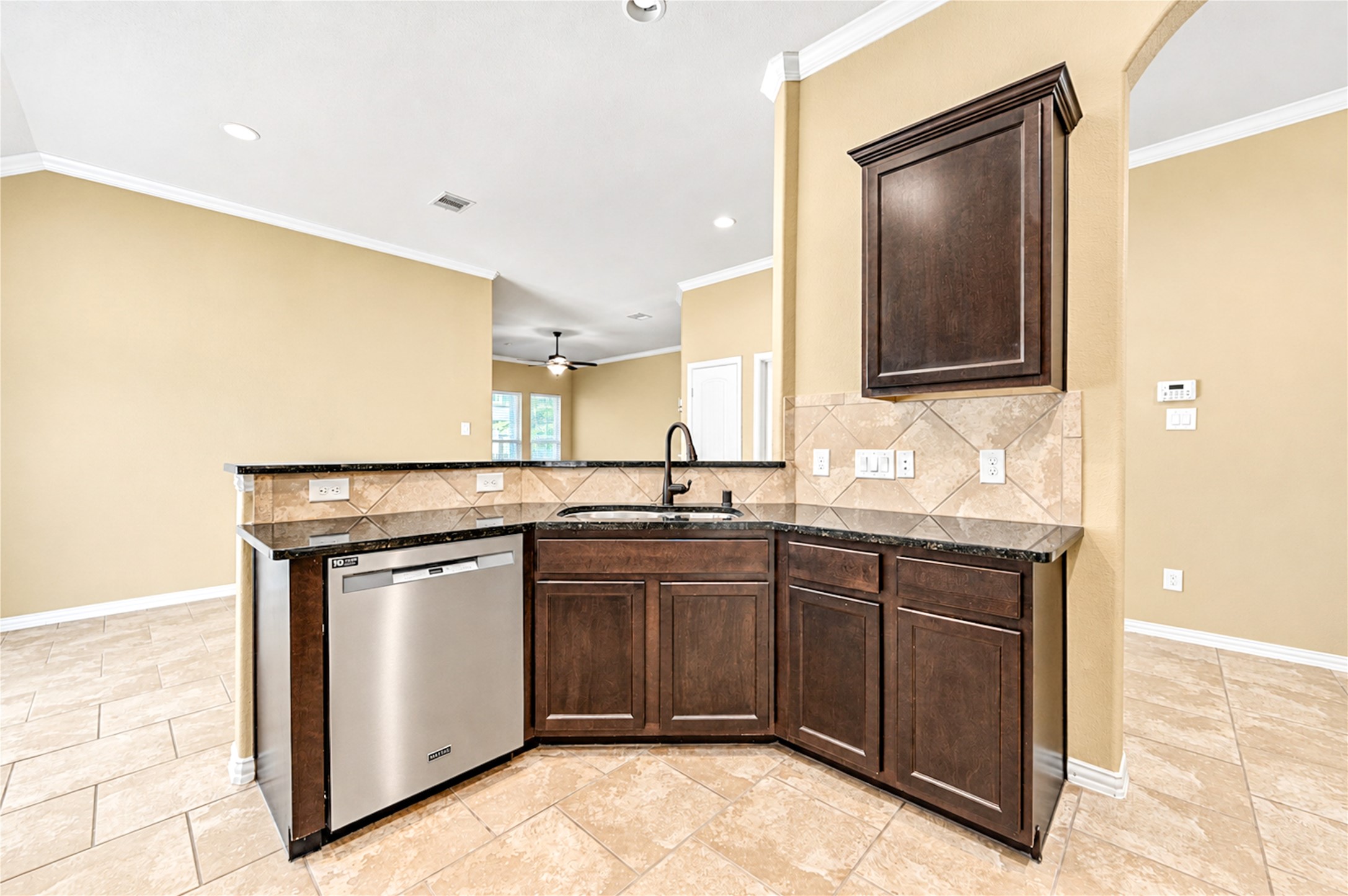 A granite peninsula with an undermount sink wraps the kitchen and keeps the cook connected to the living area.