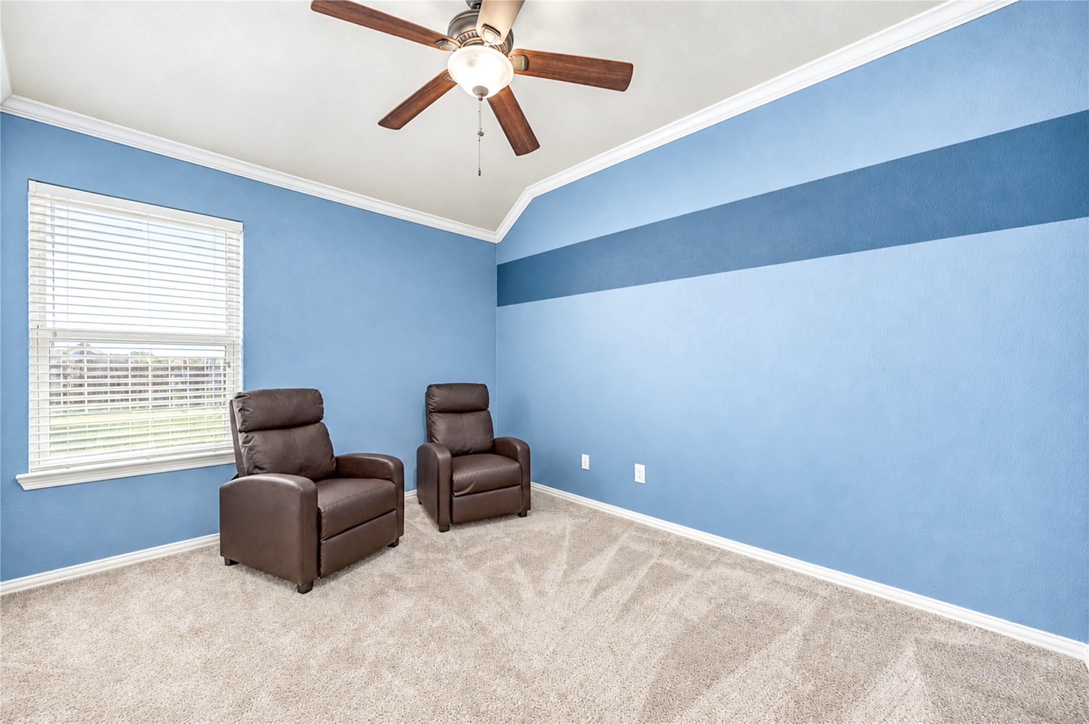 A bright corner bedroom with a ceiling fan, a large window and carpet.