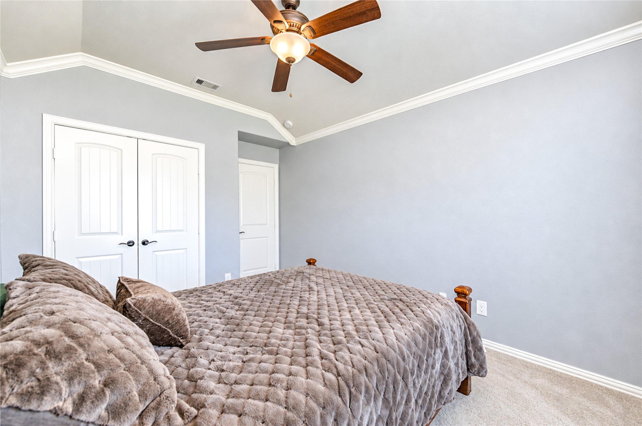 Double-door closets and a vaulted ceiling give this bedroom ample storage and height.
