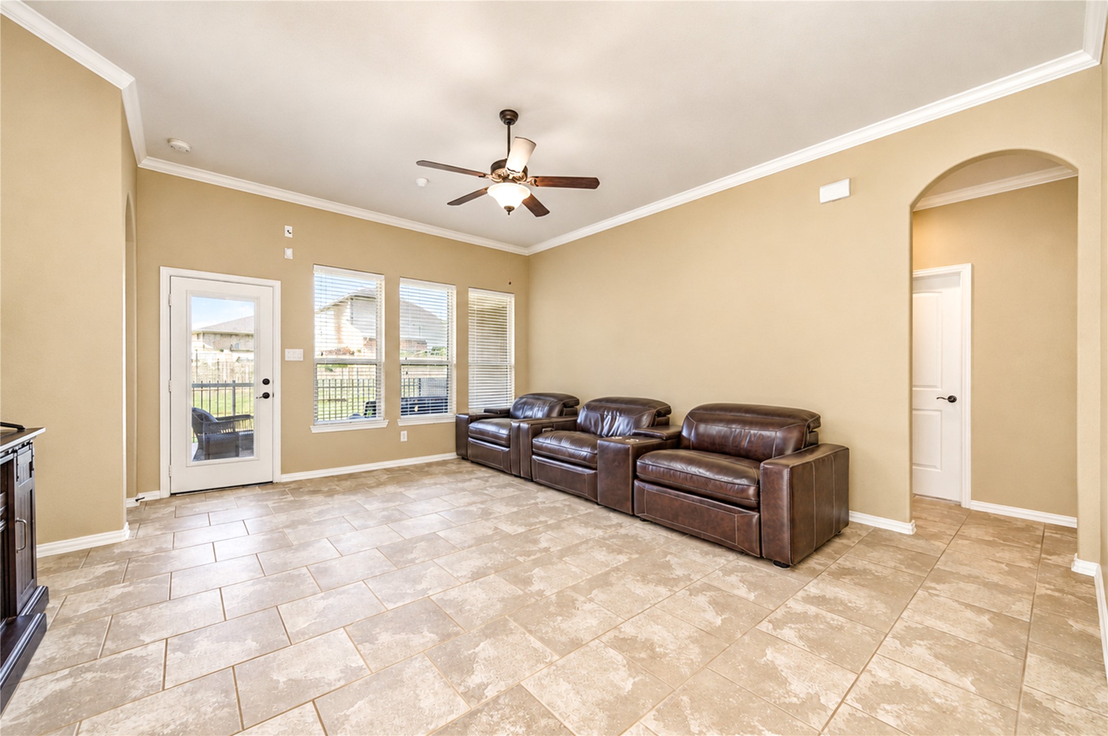 Tile floors and crown molding carry through the living room, with a door opening to the covered patio.