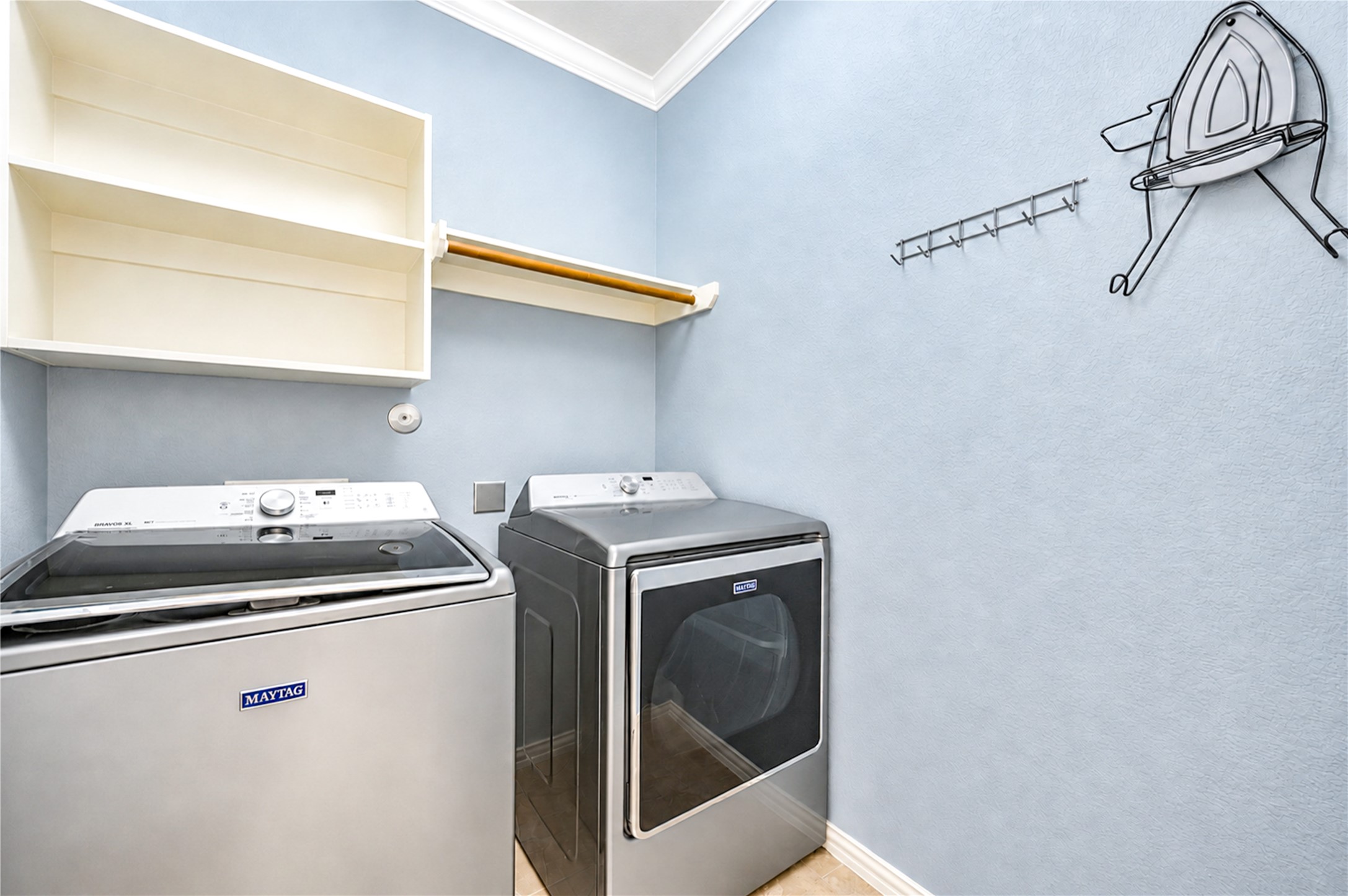 The laundry room has built-in shelving, a hanging rod and space for a full-size washer and dryer.