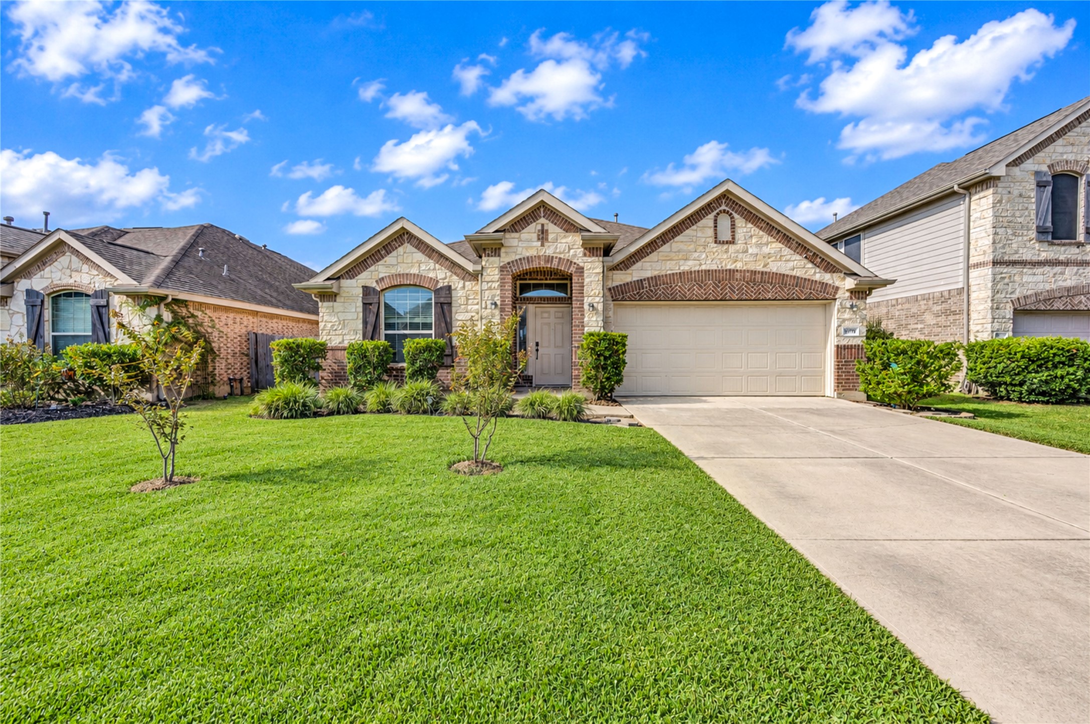 Brick and stone accents frame the arched entry beneath a layered roofline, with a lush front lawn leading to the drive. Brick and stone accents frame the arched entry beneath a layered roofline, with a lush front lawn leading to the drive.