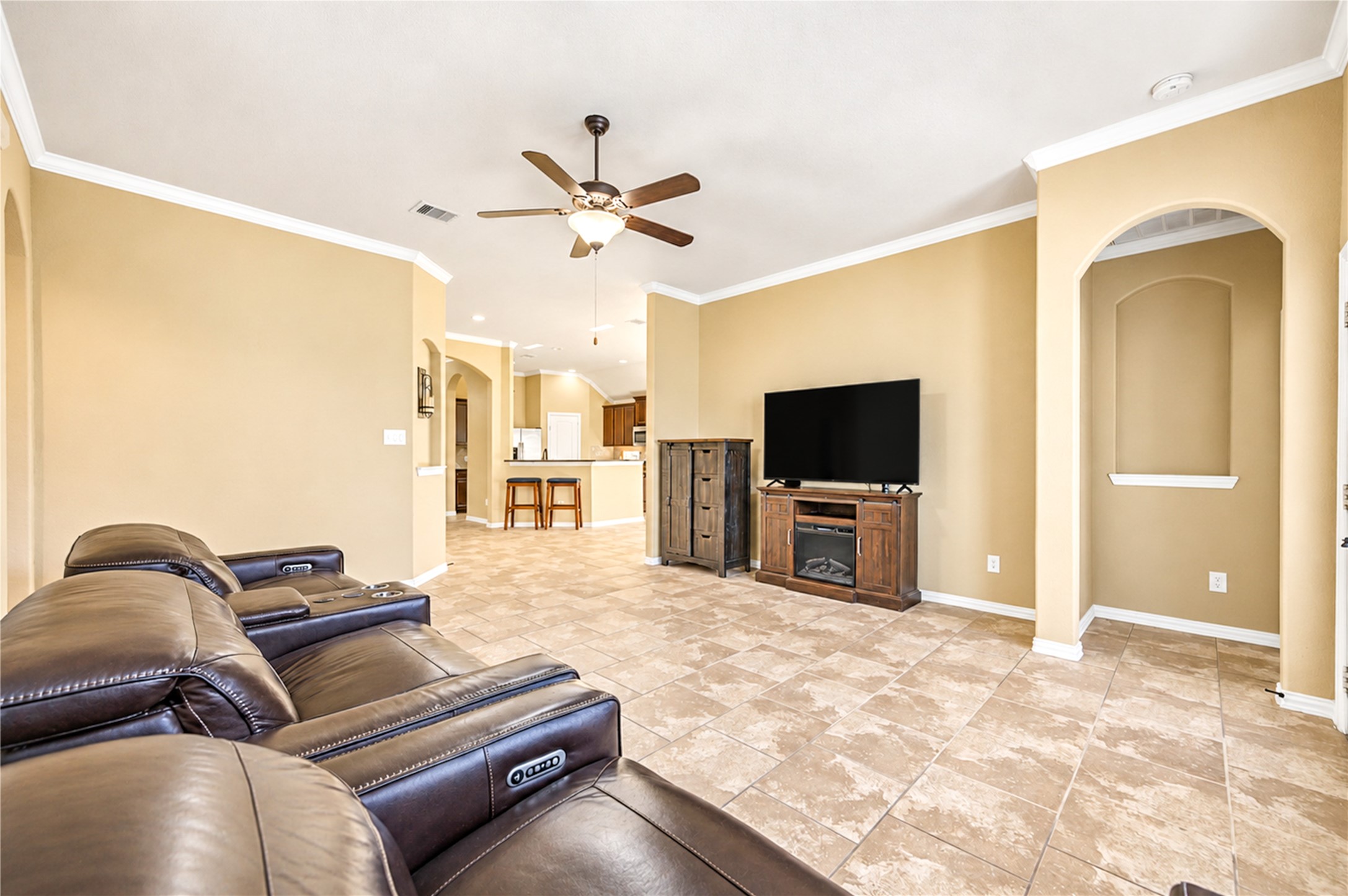 The living room opens to the kitchen and breakfast area, with an arched niche and a ceiling fan overhead.
