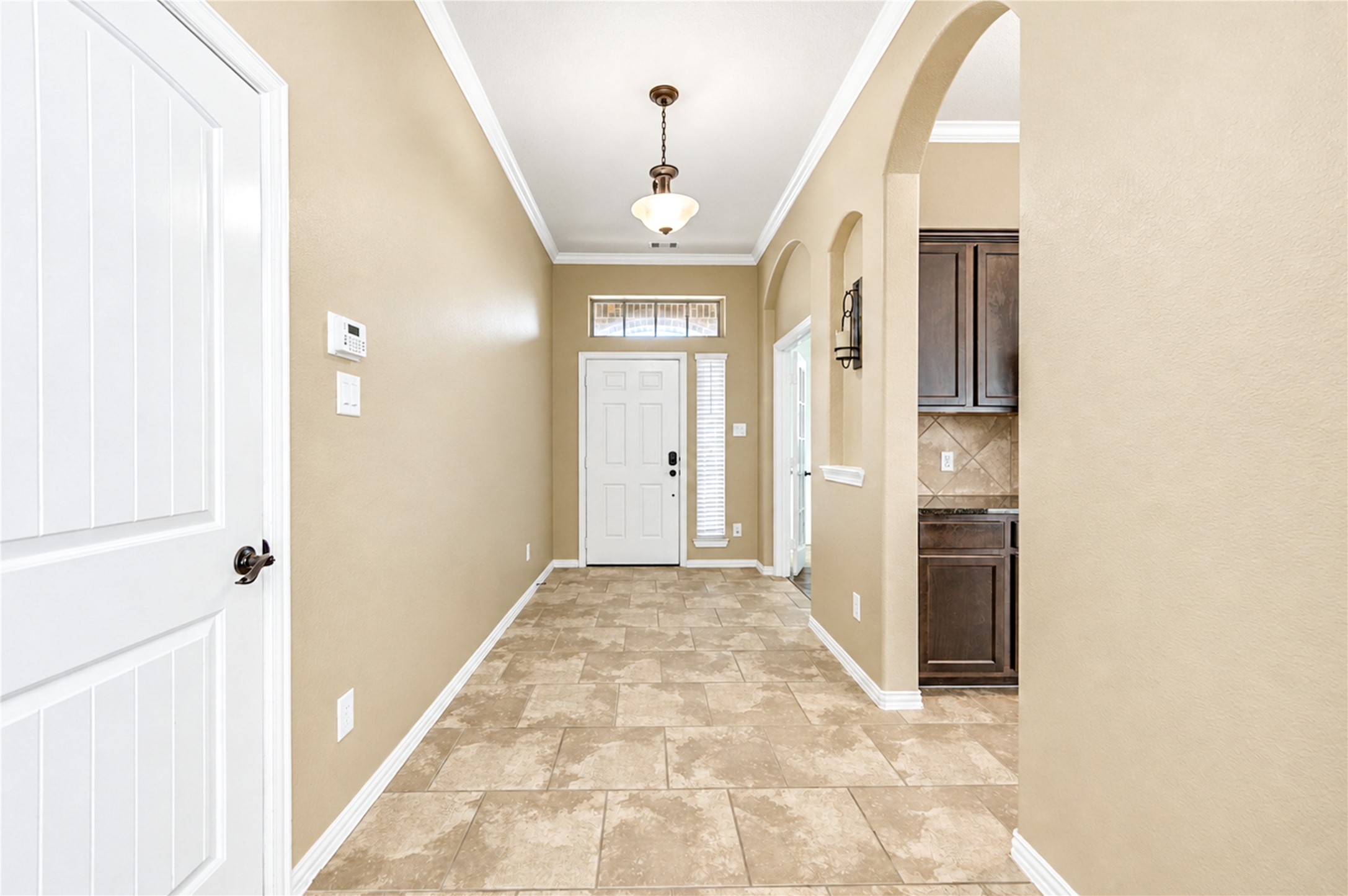 The tiled entry foyer opens through an arched passage toward the kitchen and the back of the home.
