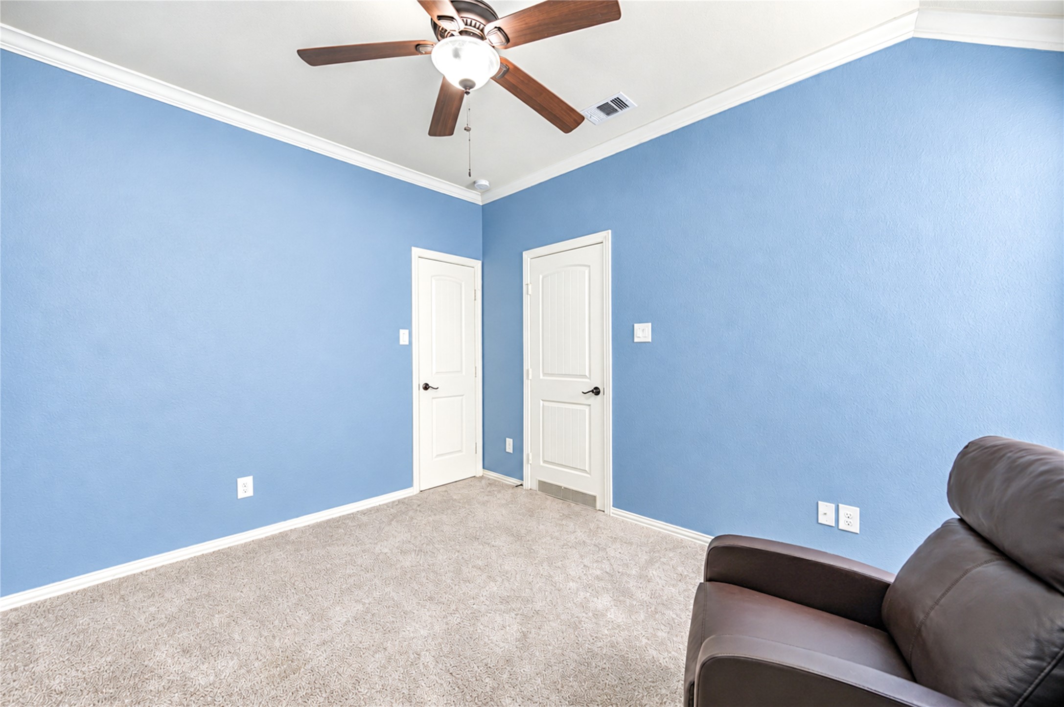 A second bedroom with crown molding, a ceiling fan and generous closet access.