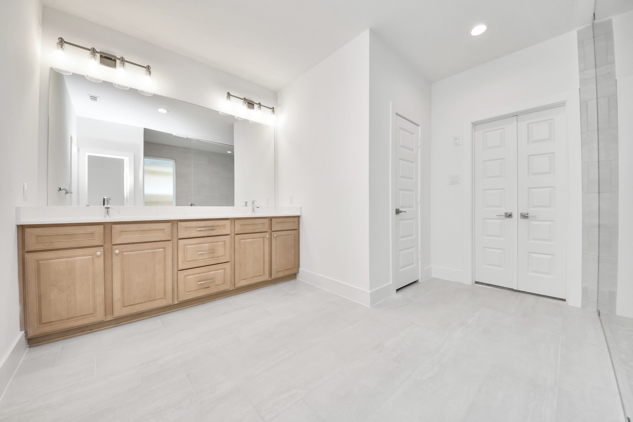 Elevate your daily routine at the elegant vanity, now equipped with double sinks, light countertops, modern hardware, and beautiful vanity lights. Sample photo of completed home with similar floor plan. Actual colors and selections may vary.