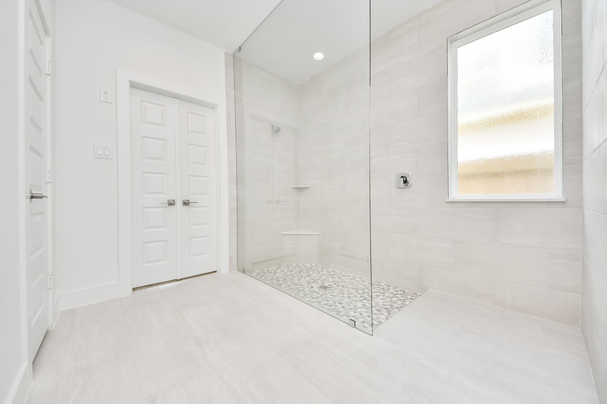 Indulge in a spa-like retreat within the confines of this primary bathroom. Delight in a spacious walk-in shower enveloped in stylish tile surround. Sample photo of completed home with similar floor plan. Actual colors and selections may vary.