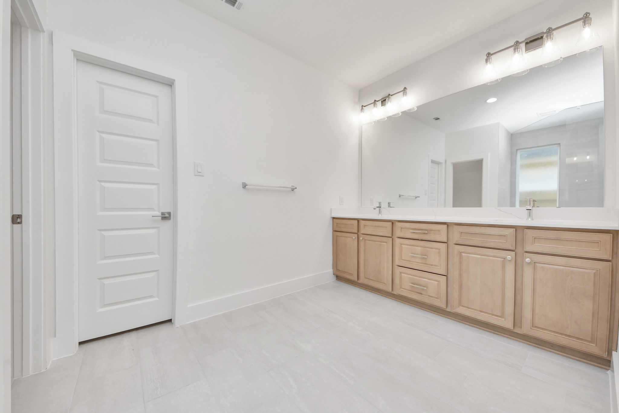 Elevate your daily routine at the elegant vanity, now equipped with double sinks, light countertops, modern hardware, and beautiful vanity lights. Sample photo of completed home with similar floor plan. Actual colors and selections may vary.