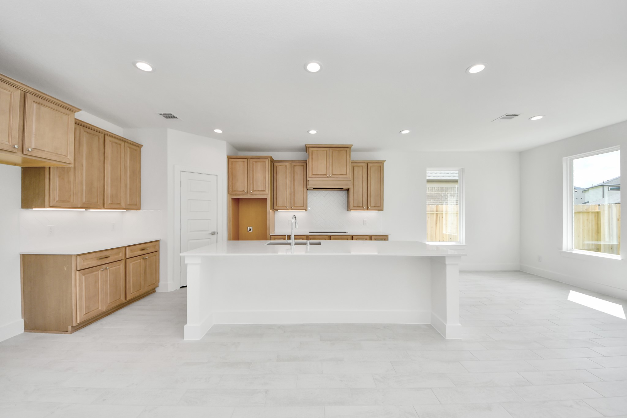 This generously spacious kitchen is a dream realized! With a massive granite island, high ceilings, soft close cabinets, granite countertops, stainless steel appliances, a sleek tile backsplash, recessed lighting, and an extended counter area, it offers both style and practicality. All this opens up to the expansive family room, creating a perfect hub for gatherings. Sample photo of completed home with similar floor plan. Actual colors and selections may vary.