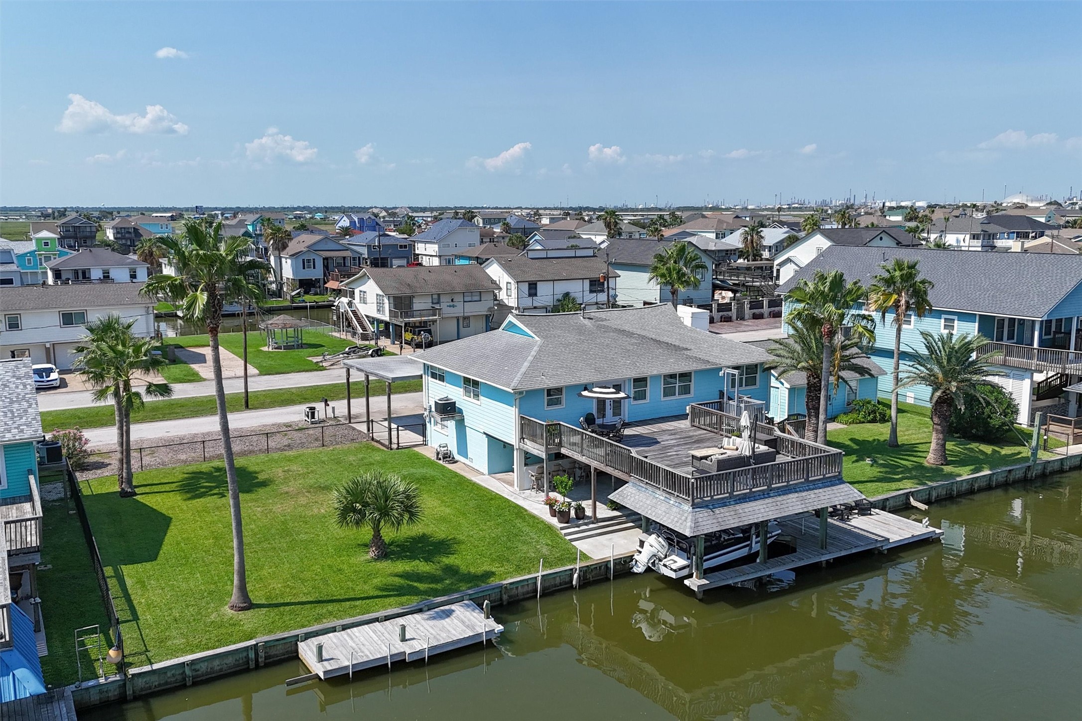 Aerial view showing the lot, home, and lot with the garage. The property has many palm trees that have been trimmed