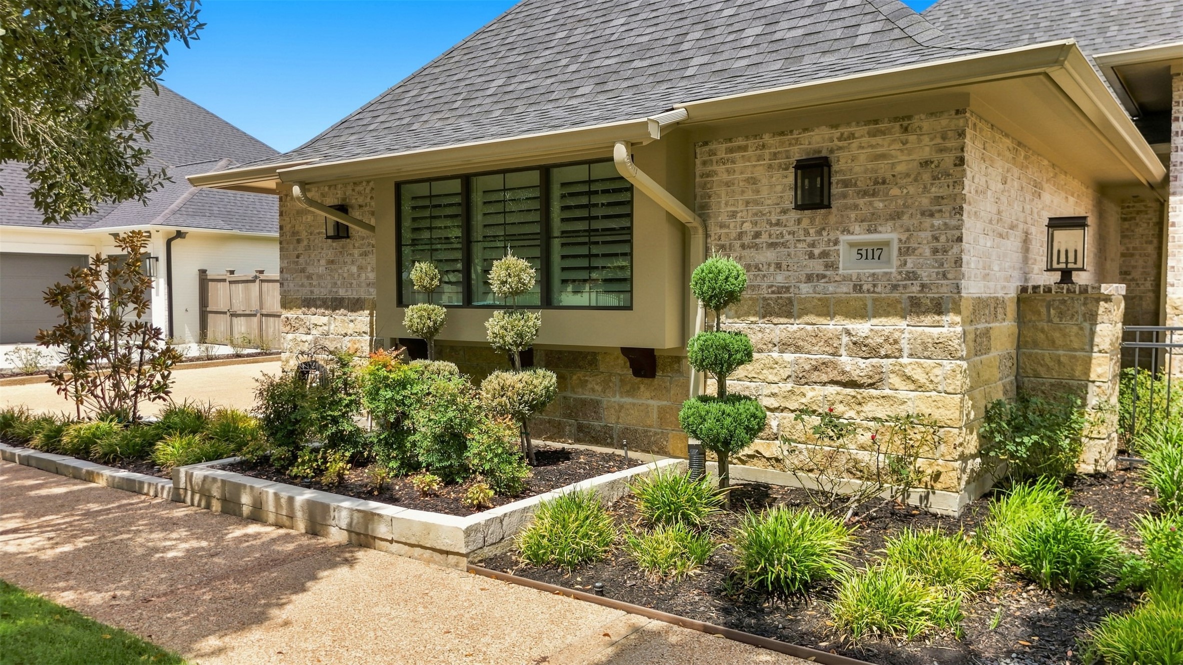 Another view of the beautifully landscaped front exterior and distinctive stone-and-brick architecture.