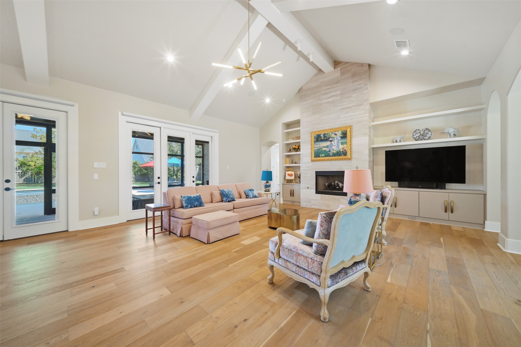 Spacious living area with soaring vaulted ceilings, gas-log fireplace with tile surround, and custom built-in cabinetry.