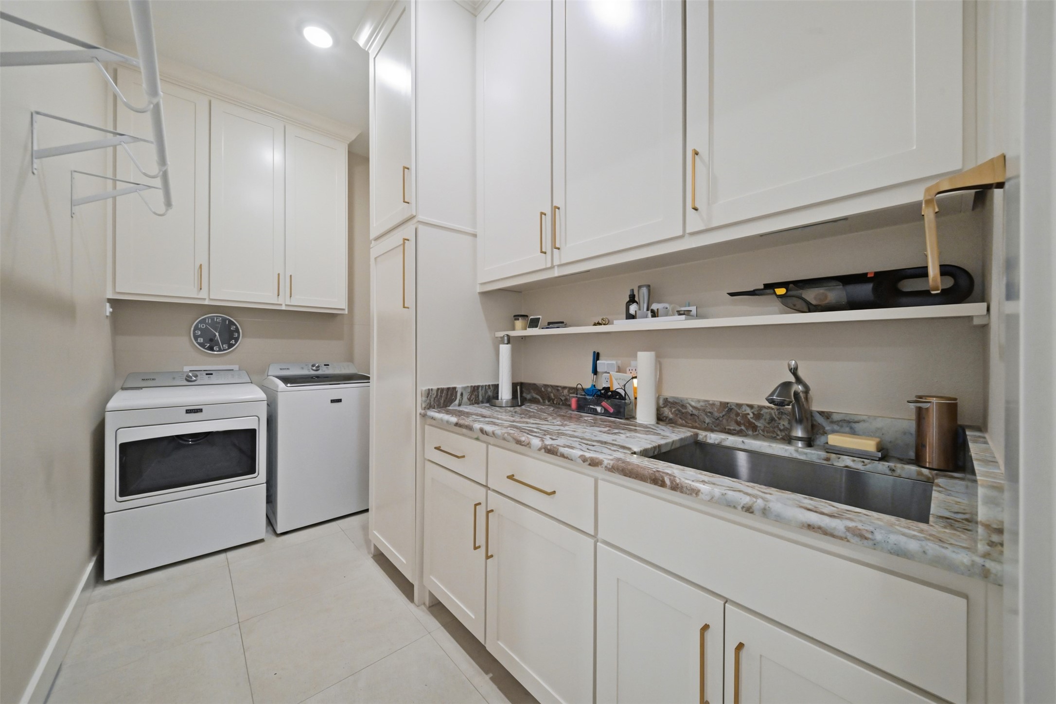 Spacious laundry room with an oversized single-basin sink, abundant cabinetry and hanging space, plus direct access from the primary closet for added convenience.