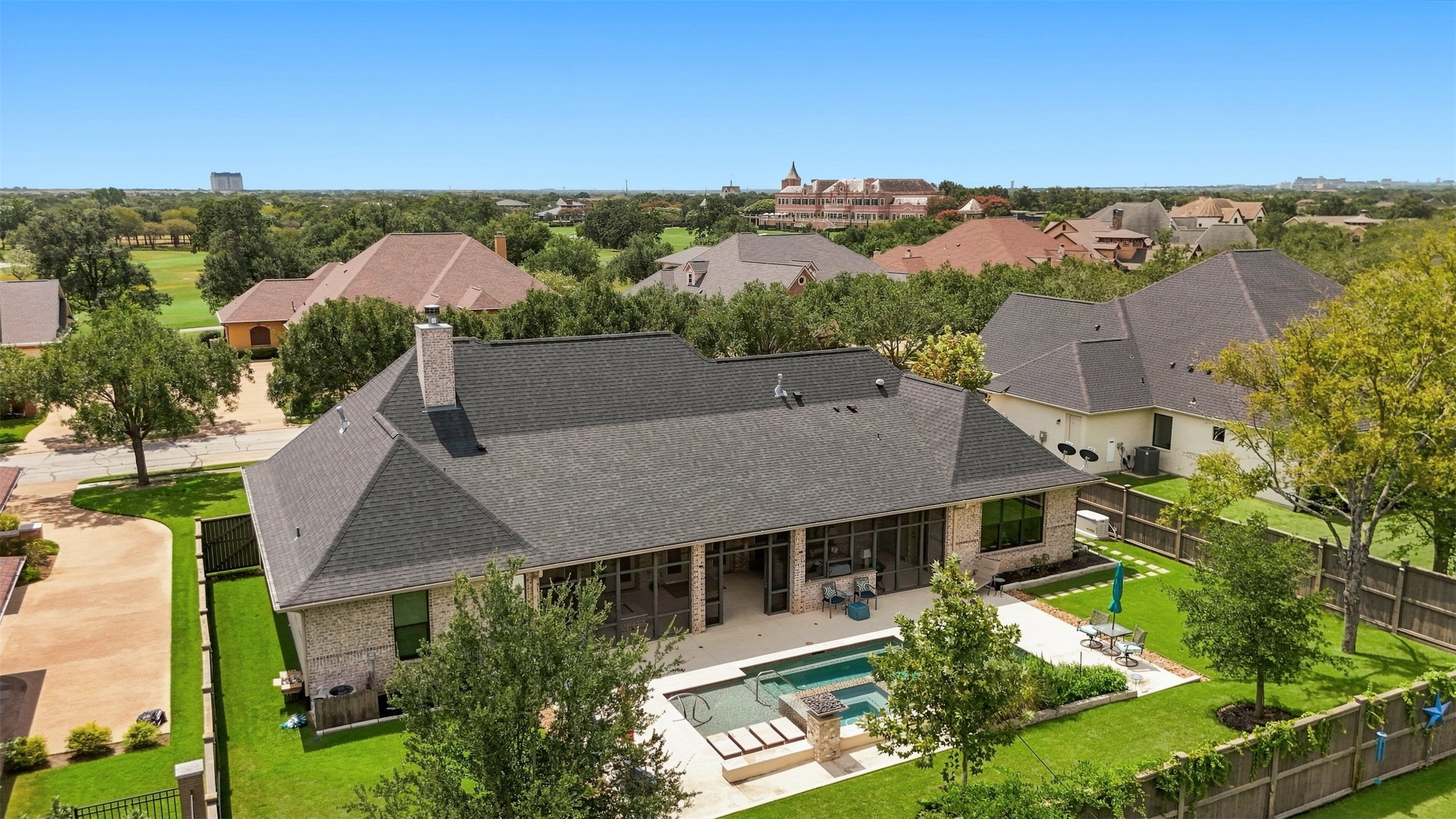 Aerial view of the home showcasing the private backyard, pool, screened porch, and beautifully maintained grounds.