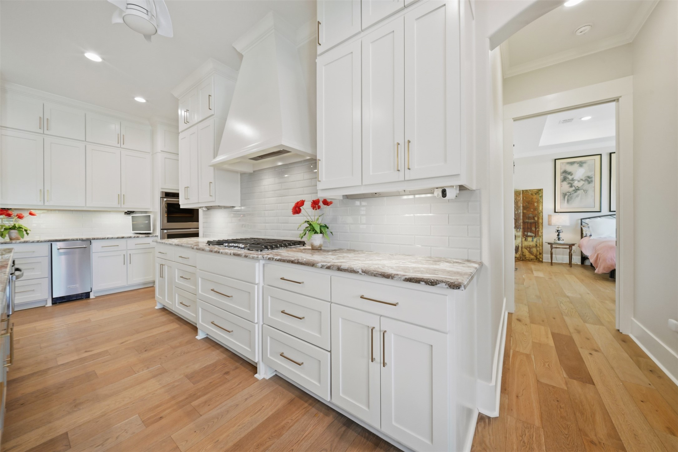 Beautifully appointed kitchen featuring a gas cooktop, custom vent hood, marble countertops, and abundant custom cabinetry.