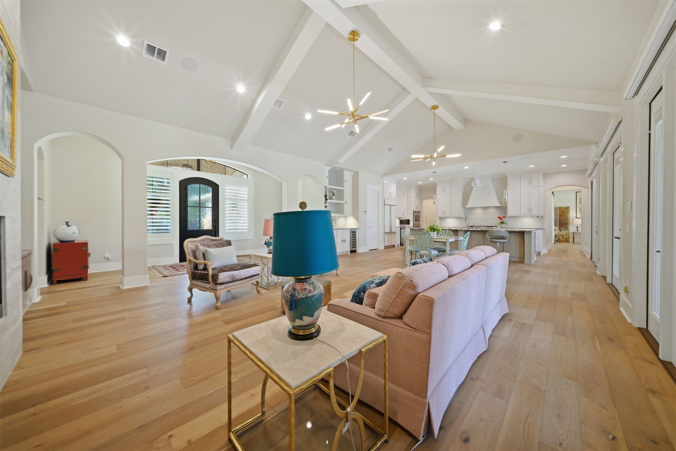 Open-concept great room with soaring cathedral ceiling and hardwood floors, flowing into the dining space and kitchen.