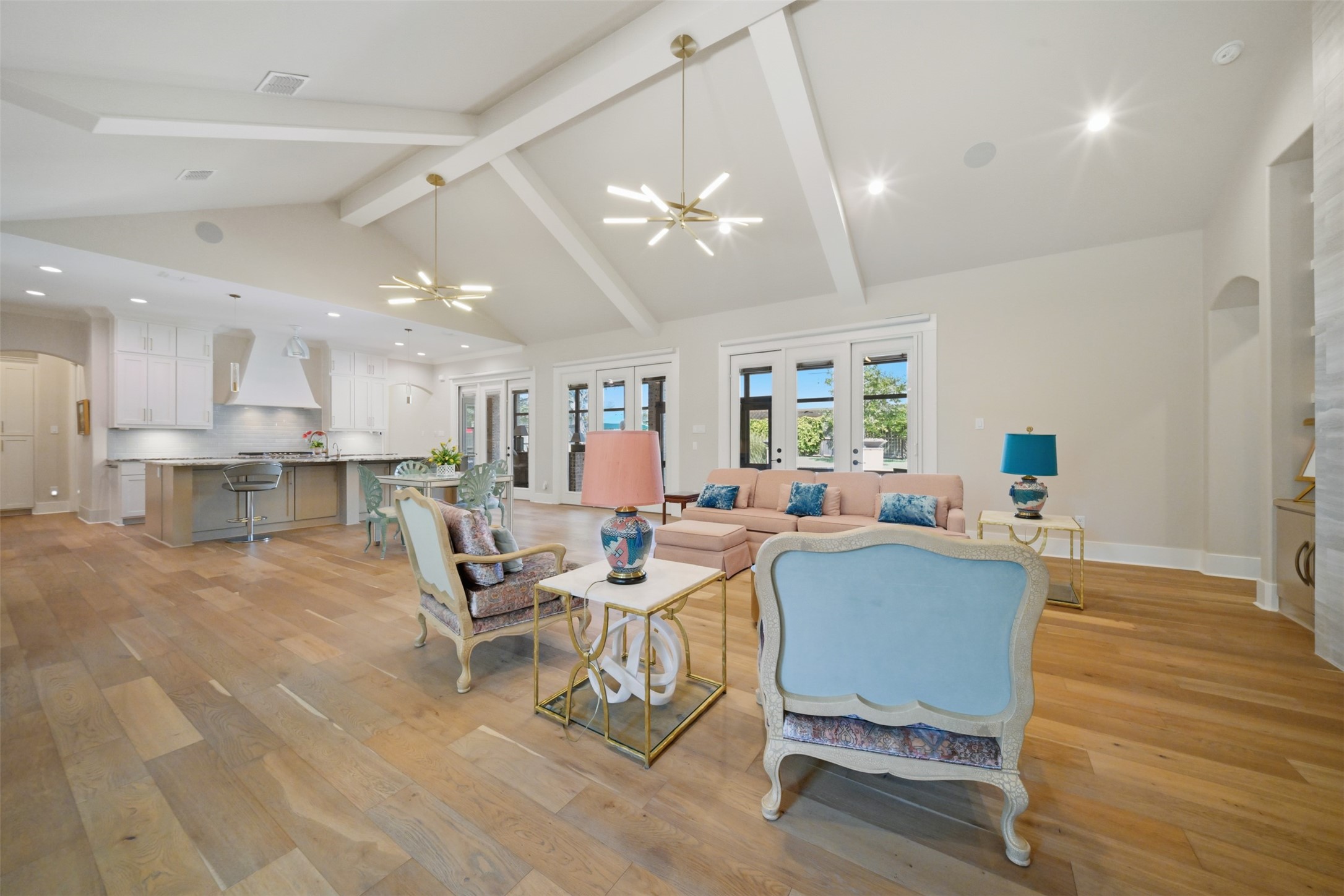 Expansive open-concept living, dining, and kitchen areas with soaring ceilings and seamless access to the screened porch and pool beyond.