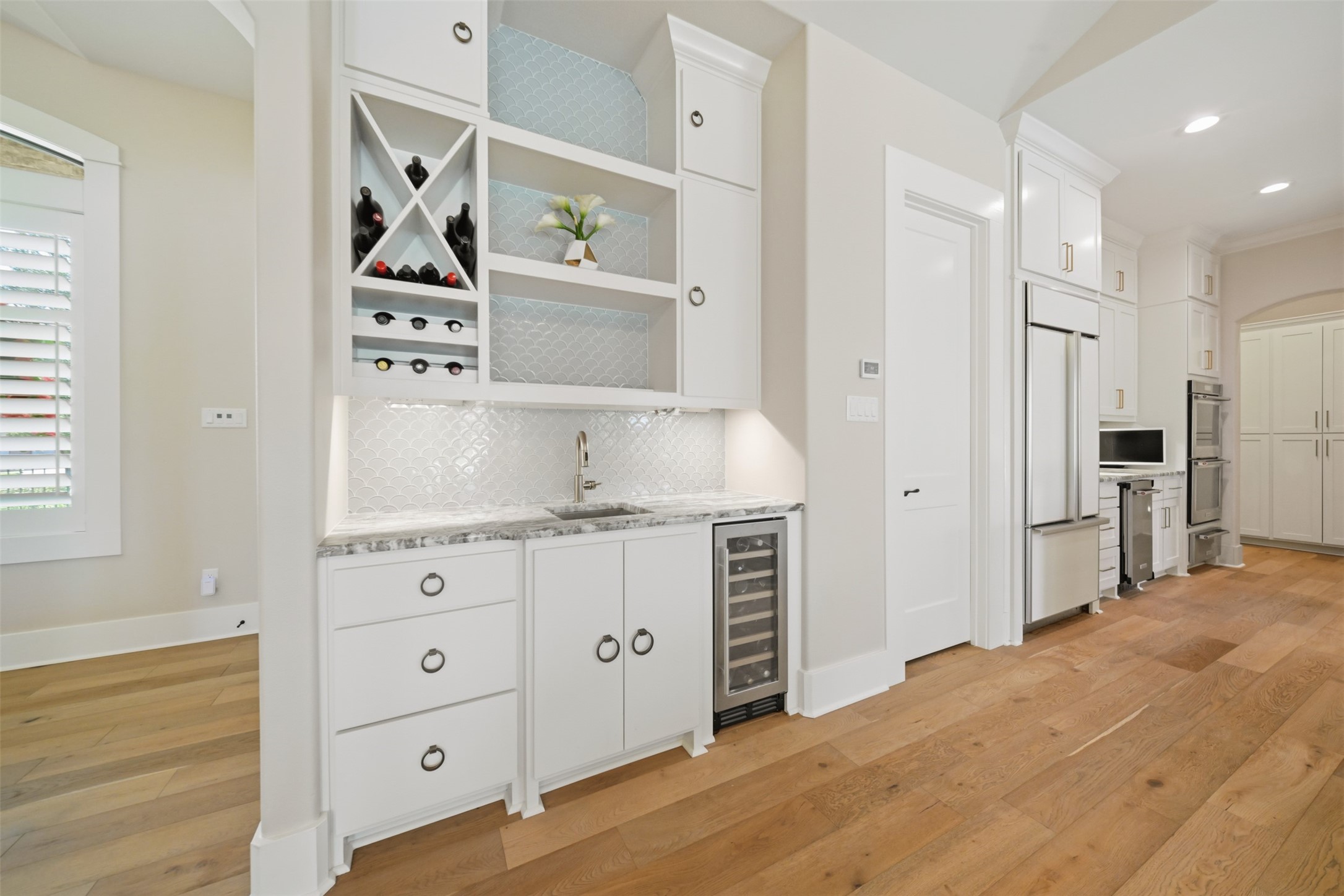 Wet bar featuring a sink, custom cabinetry, built-in wine refrigerator, and dedicated wine storage.