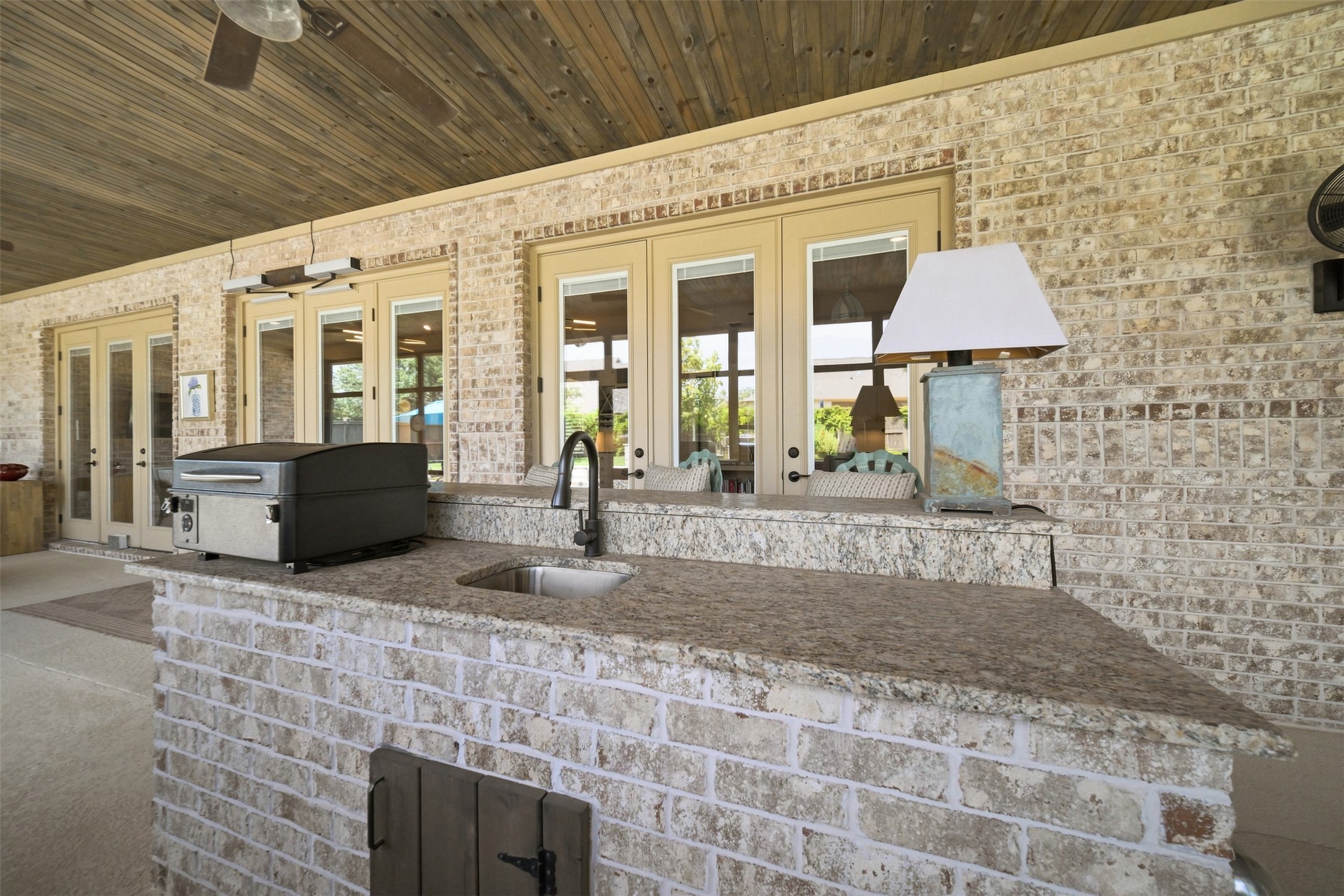 Screened-in patio features a built-in outdoor kitchen with grill, sink and generous counter space overlooking the backyard and pool.