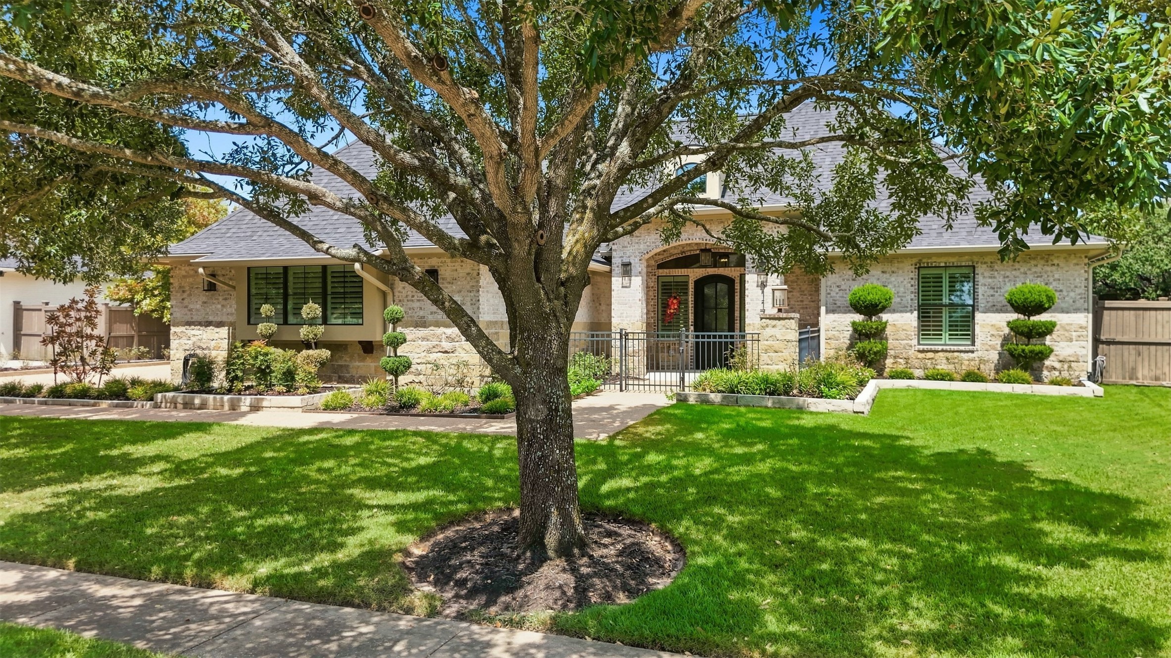 Beautiful curb appeal with mature shade tree and lush landscaping.