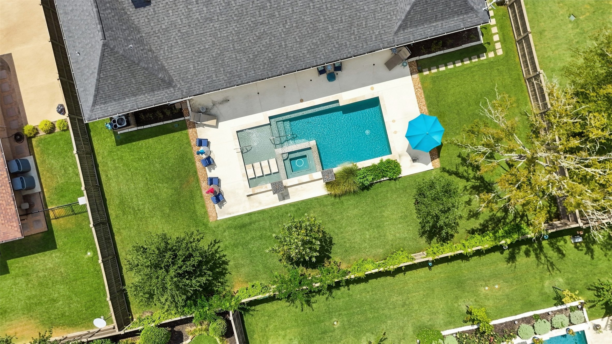 Aerial view showcasing the private backyard, pool and spa, multiple lounging areas, and generous green space.