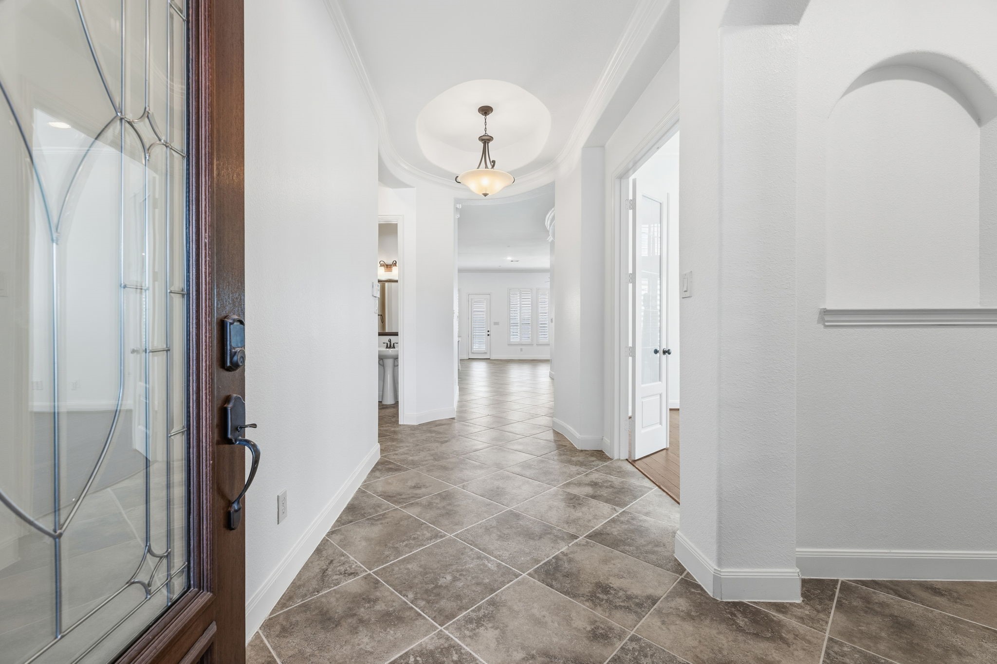 Step into a welcoming entryway featuring tile flooring, a stylish light fixture, and a view into the bright, open living area Step into a welcoming entryway featuring tile flooring, a stylish light fixture, and a view into the bright, open living area