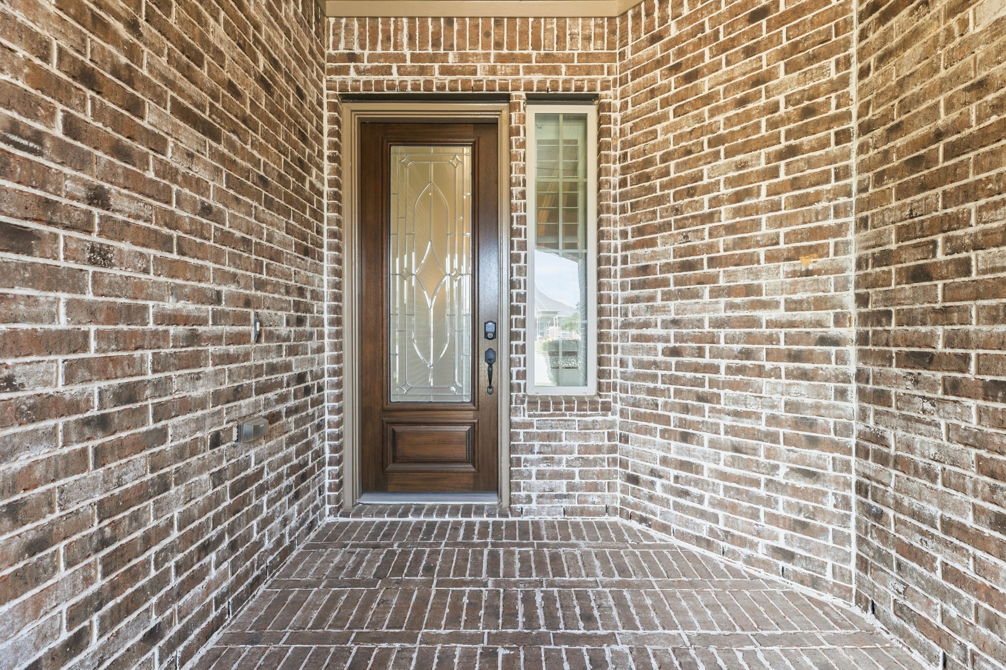 Brick front porch with a beautiful wooden door featuring decorative glass panels Brick front porch with a beautiful wooden door featuring decorative glass panels