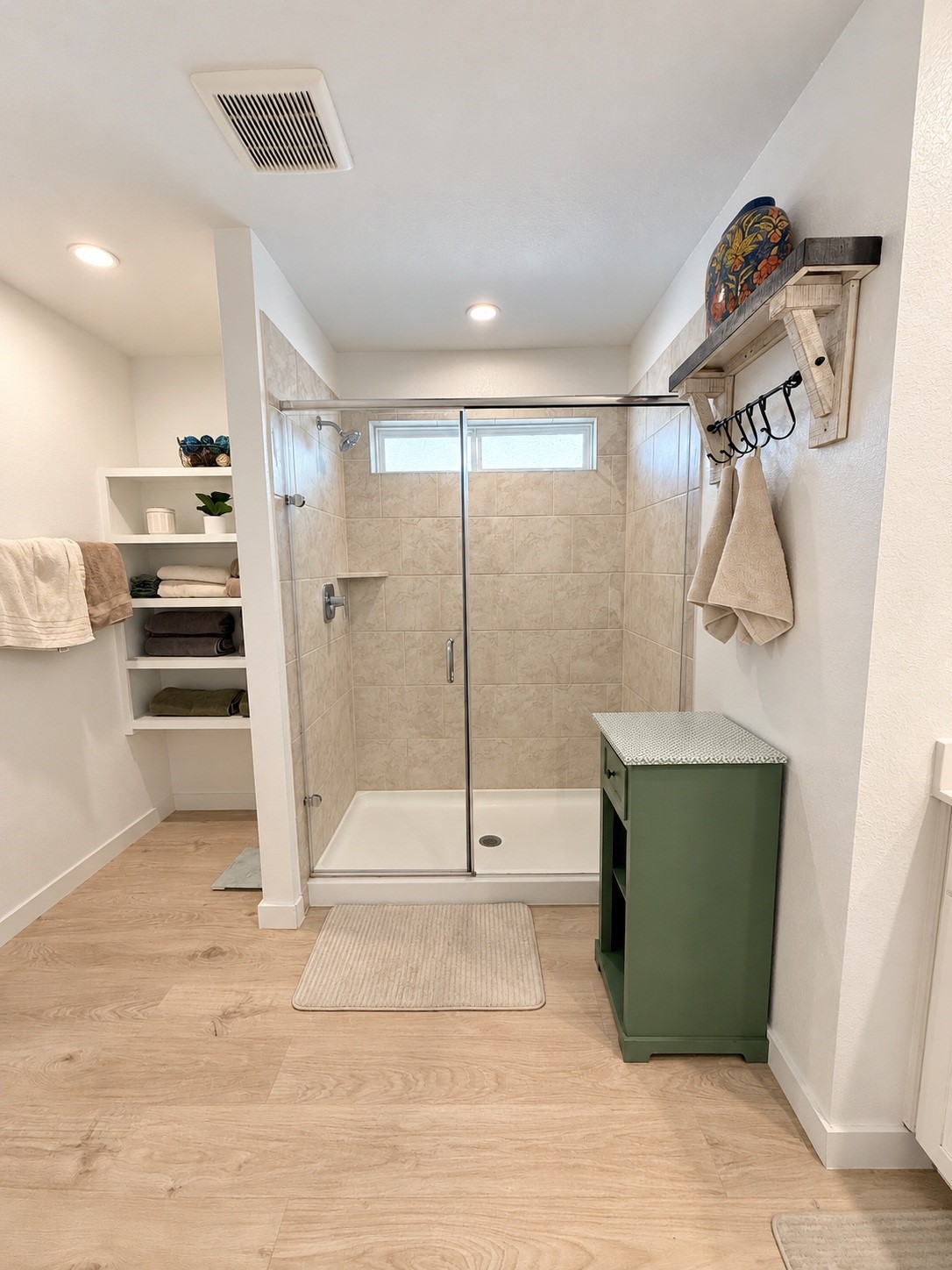 Spacious Primary Bathroom with Glass-Enclosed Walk-In Shower and Built-In Linen Shelves.