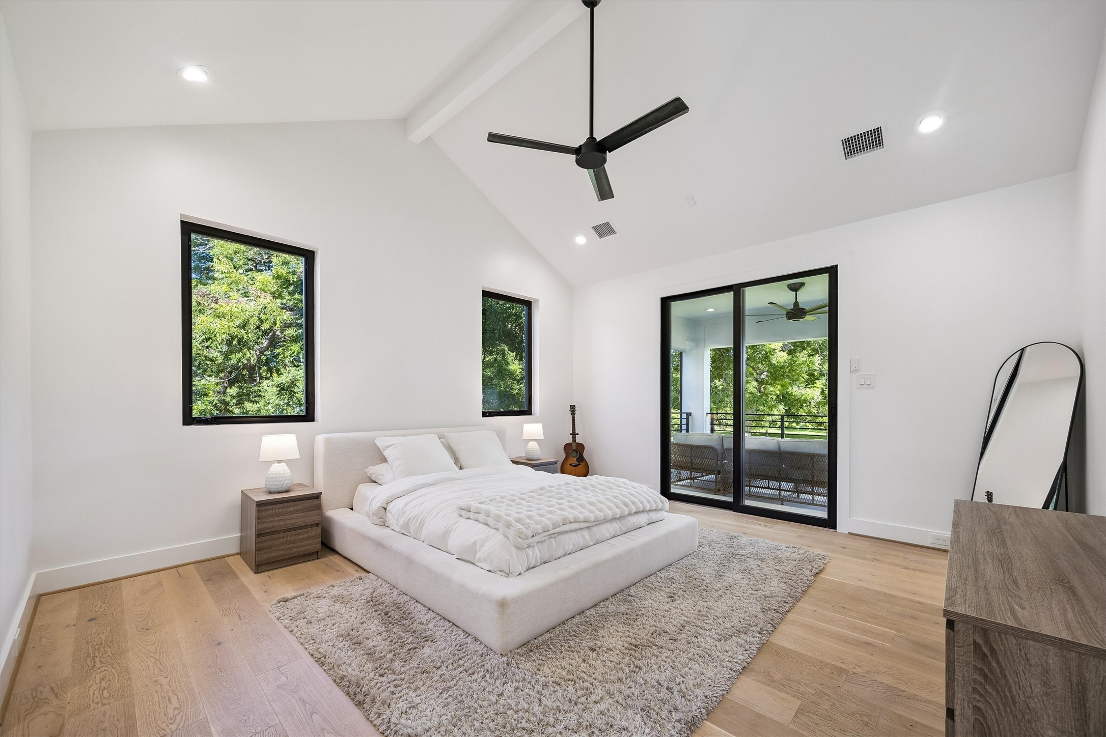 Soaring ceilings, abundant natural light, and expansive glass doors opening toward a private balcony create a peaceful retreat with a delightful connection to the outdoors.