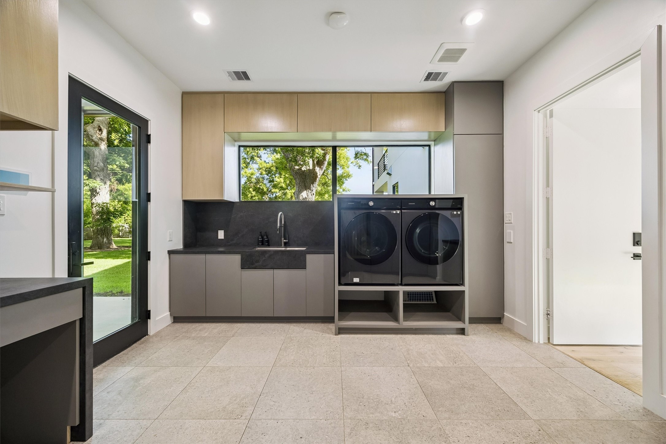Function meets refined design in this spacious laundry room, complete with generous cabinetry, modern appliances, and a large window overlooking the picturesque grounds.