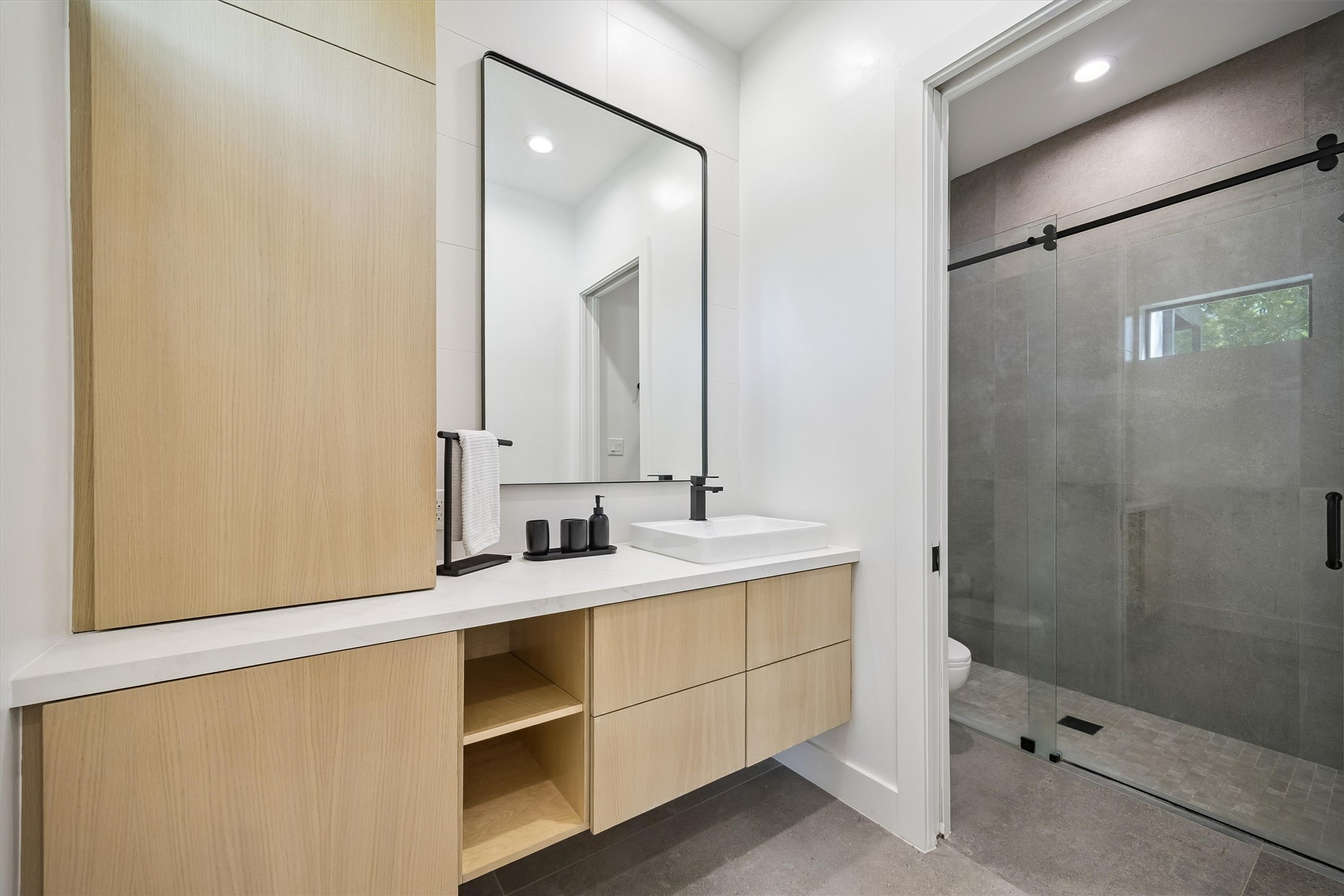 Contemporary cabinetry, a floating vanity, and a beautifully finished glass-enclosed shower create a refined private bathroom with a clean, timeless aesthetic.