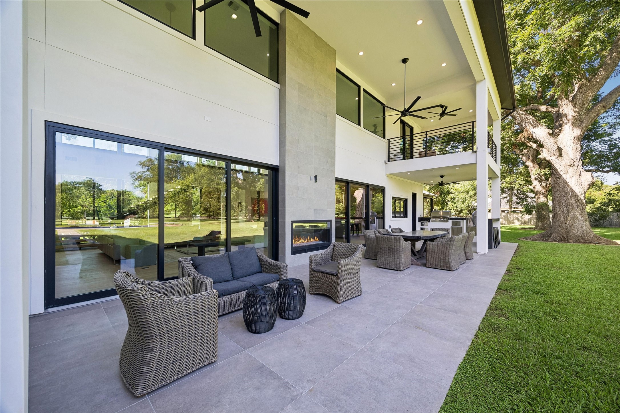 The home's impressive covered terrace extends the living experience outdoors, where comfortable seating, a contemporary fireplace, and lush estate views create an inviting atmosphere for year-round enjoyment.