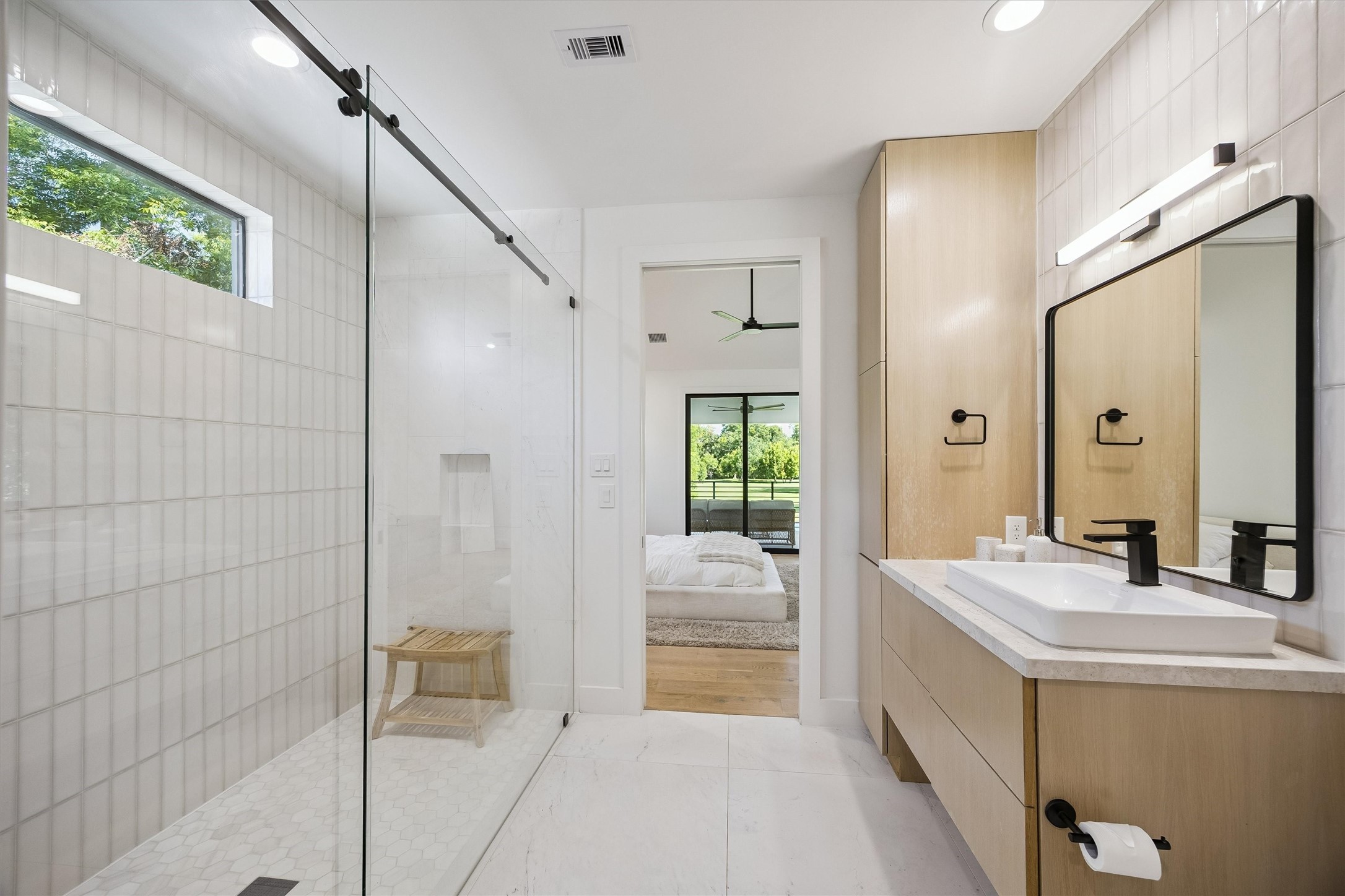 A beautifully finished bathroom combines a spacious glass-enclosed shower, elegant cabinetry, and thoughtfully selected fixtures, providing comfort and sophistication for guests or family.
