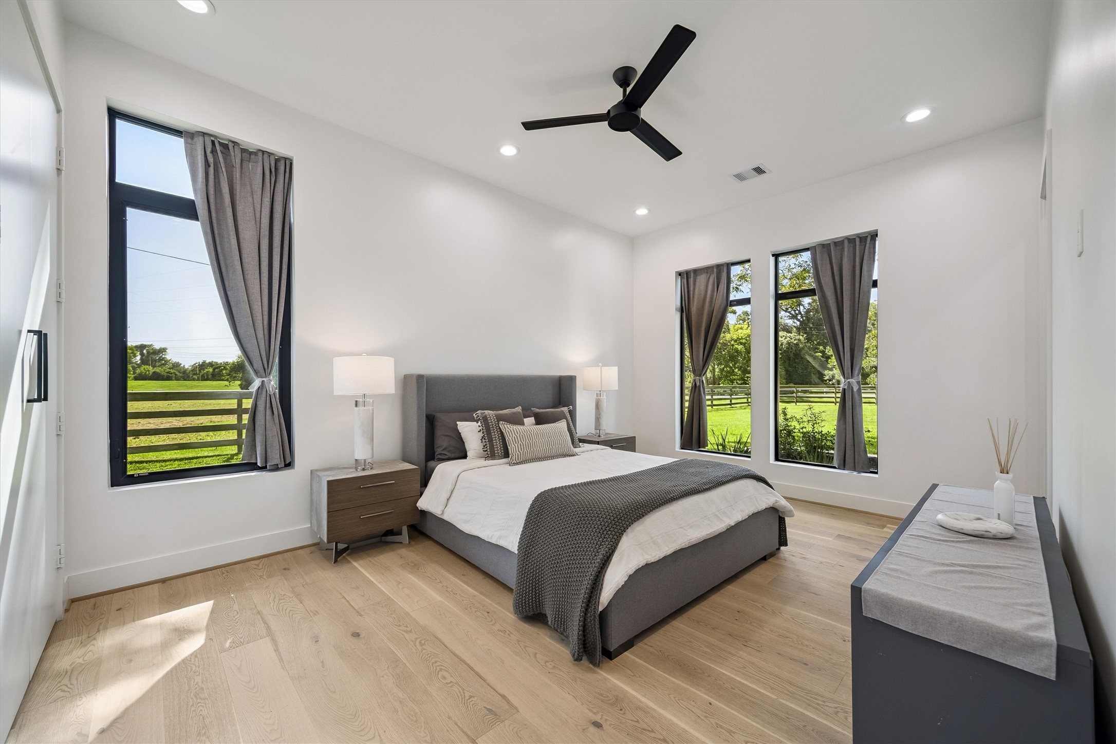 Beautifully proportioned and filled with natural light, this inviting bedroom offers tranquil garden views, warm wood flooring, and a sophisticated contemporary atmosphere.