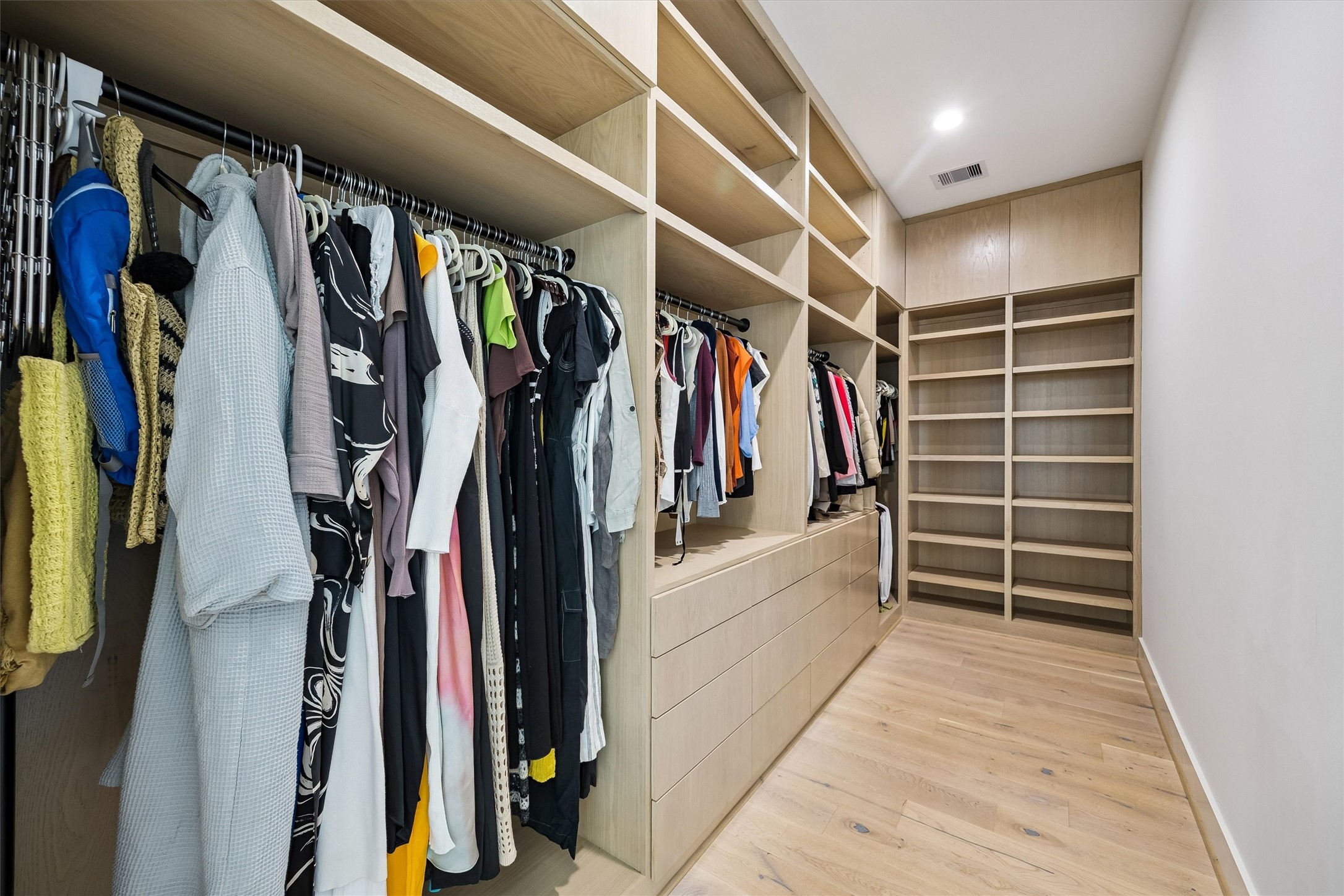 A second generously proportioned dressing room features extensive custom shelving, hanging space, and elegant wood finishes, offering exceptional organization and convenience.