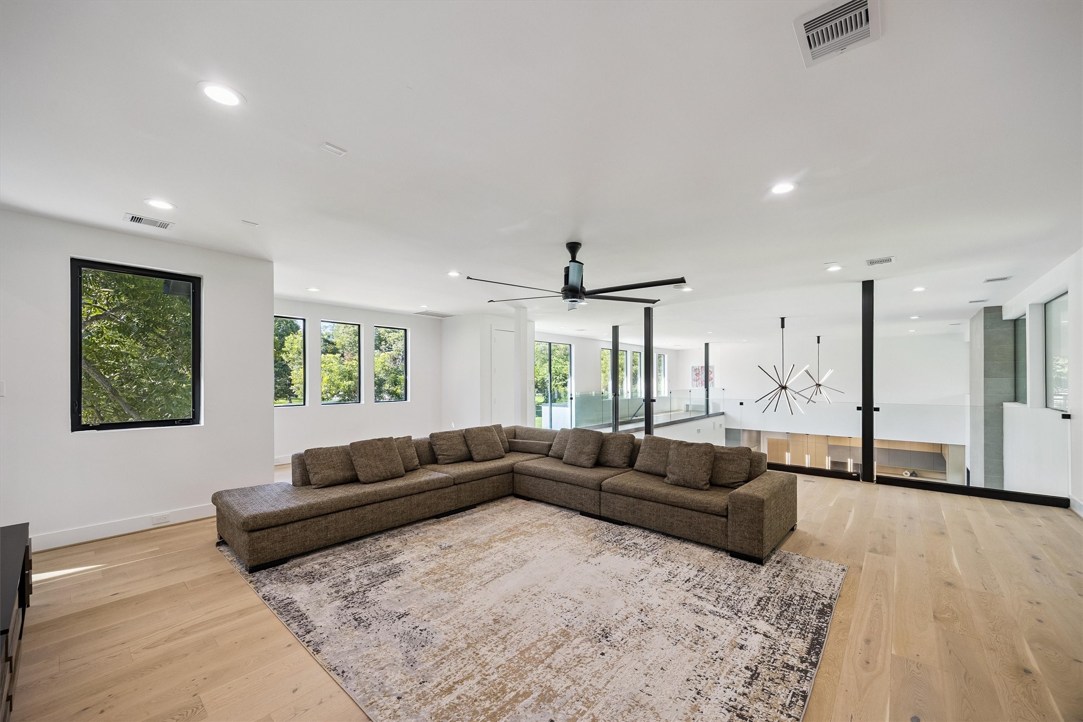 A generous secondary living space offers endless possibilities for recreation, relaxation, or entertaining, with beautiful wood flooring, contemporary lighting, and an open, comfortable layout.