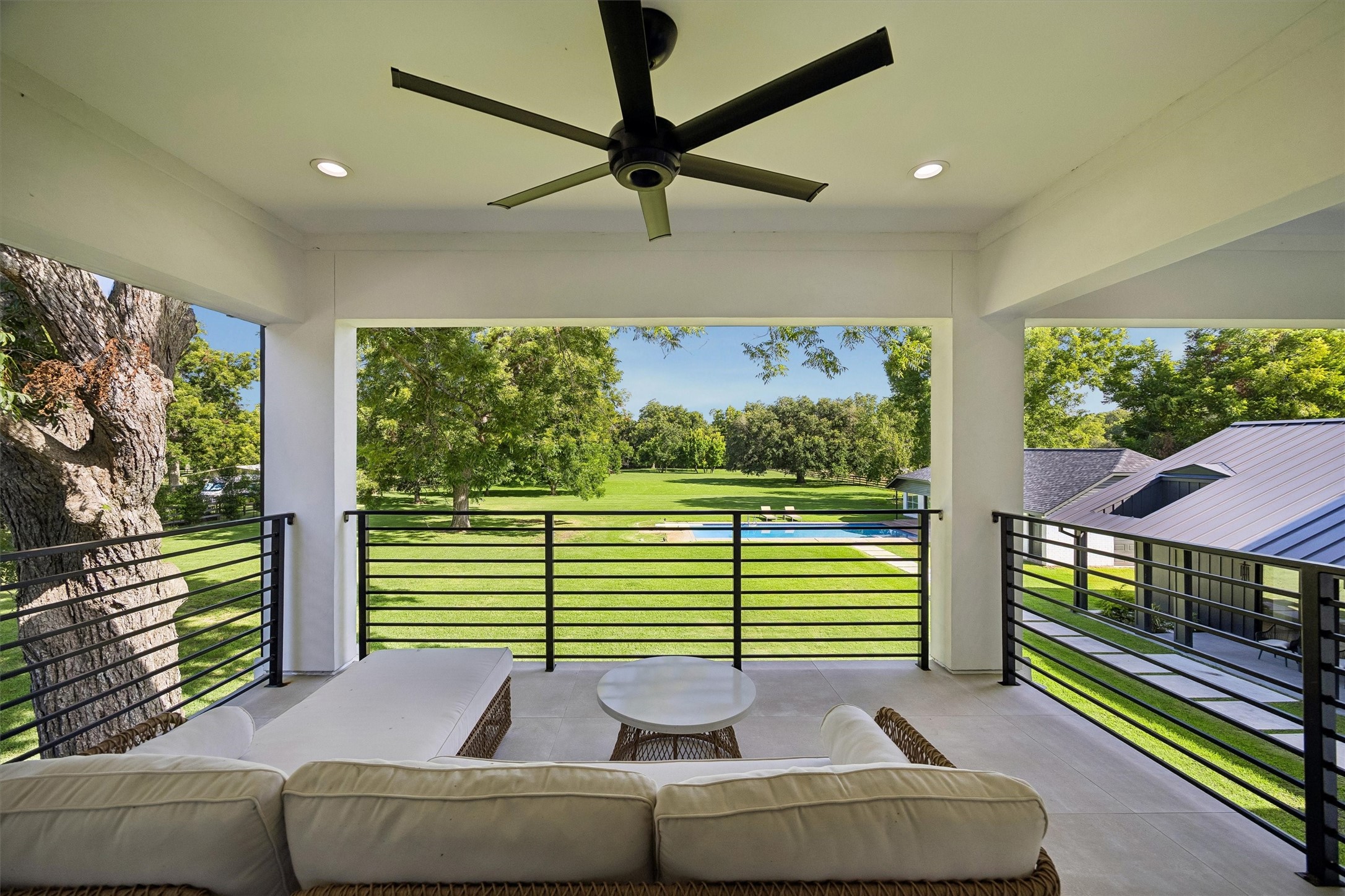 An inviting covered balcony offers a front-row seat to the estate's expansive green landscape, providing a peaceful setting for morning coffee, evening relaxation, or simply enjoying the scenery.