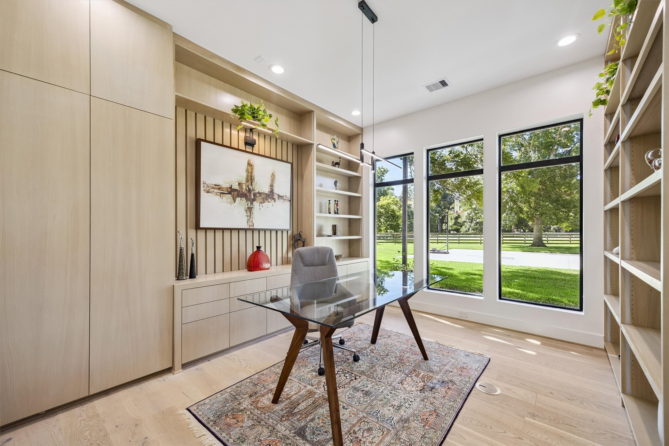 An inspiring retreat for work or quiet reflection, this beautifully appointed study features custom shelving, elegant built-ins, and expansive windows framing peaceful views of the surrounding landscape.