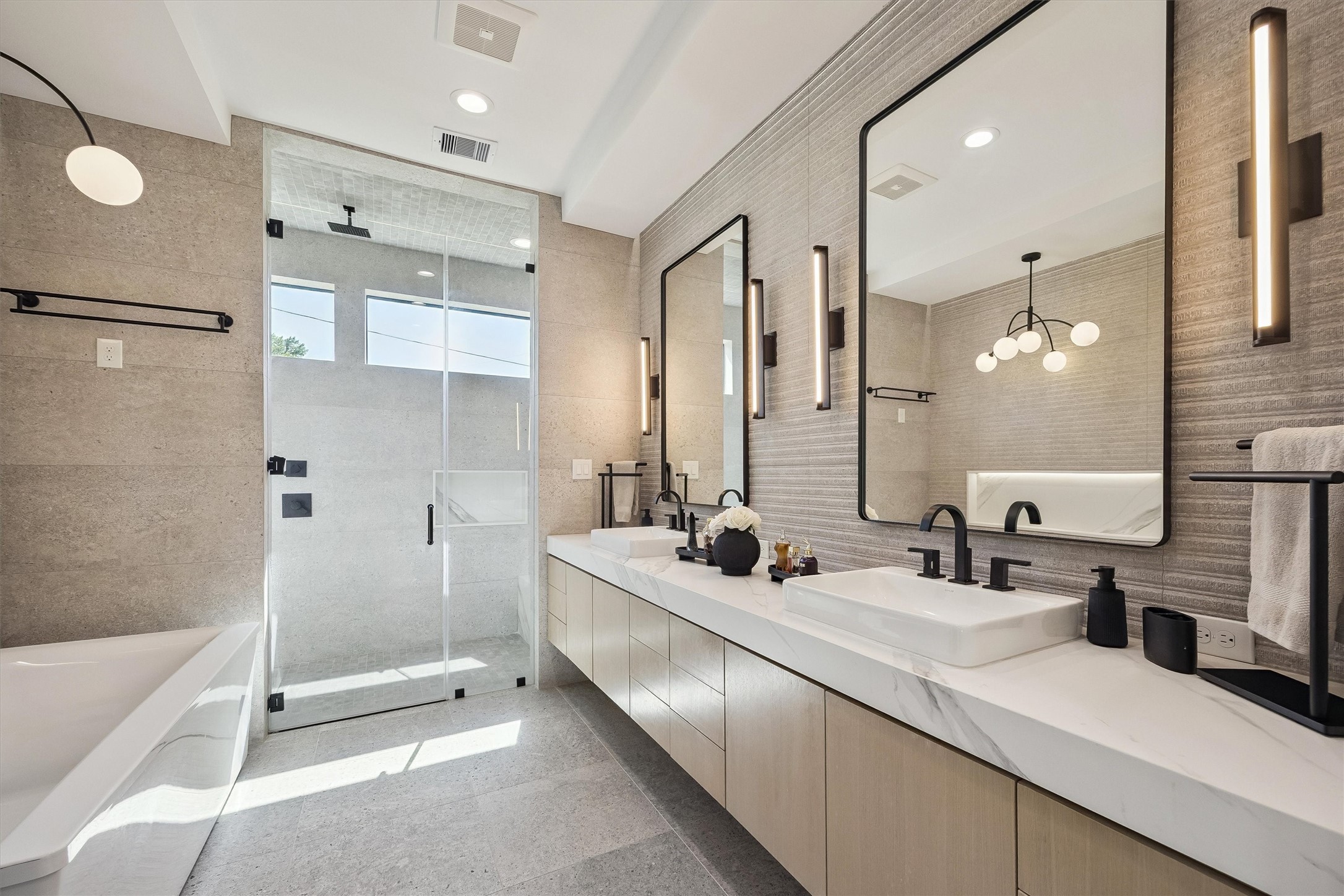 A refined combination of elegant finishes, dual vanities, contemporary lighting, and a glass-enclosed shower transforms the primary bath into a luxurious daily retreat.