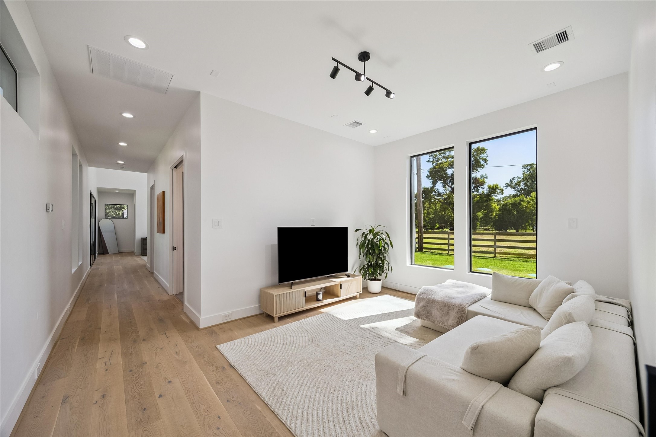 A serene sitting area within the primary wing offers a peaceful escape, where expansive windows invite natural light and showcase the beautifully landscaped grounds.