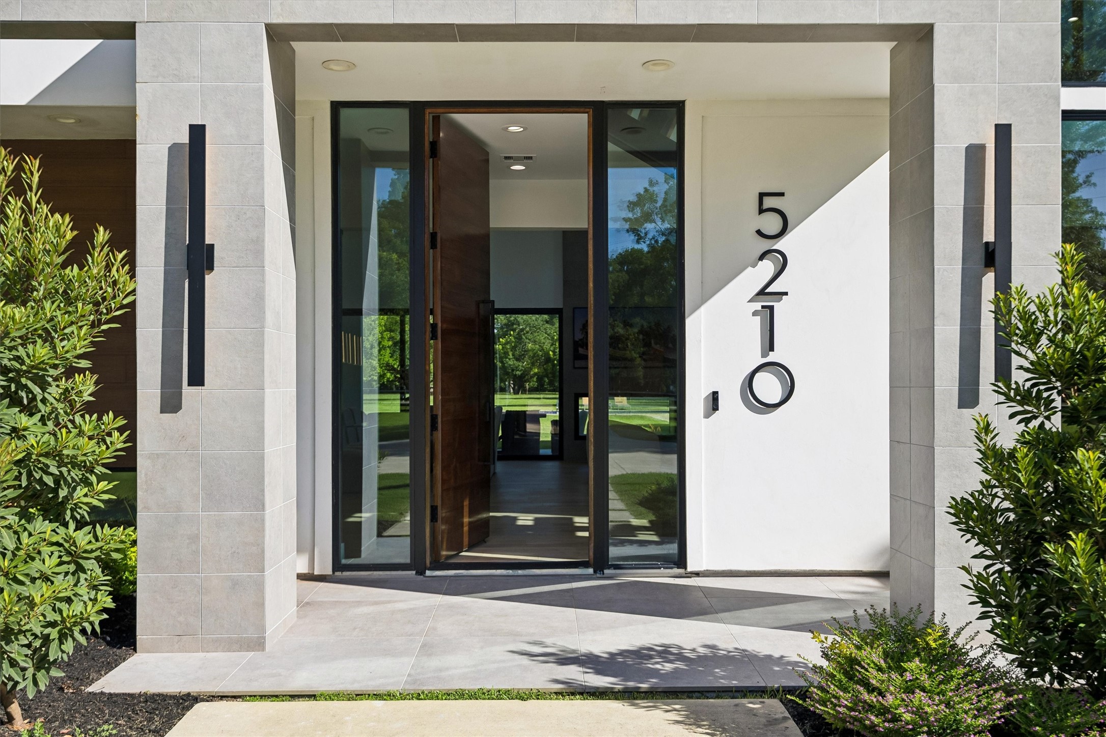 A striking glass entry framed by clean architectural lines sets the tone for the sophisticated interiors beyond, while offering an inviting connection to the surrounding landscape. A striking glass entry framed by clean architectural lines sets the tone for the sophisticated interiors beyond, while offering an inviting connection to the surrounding landscape.