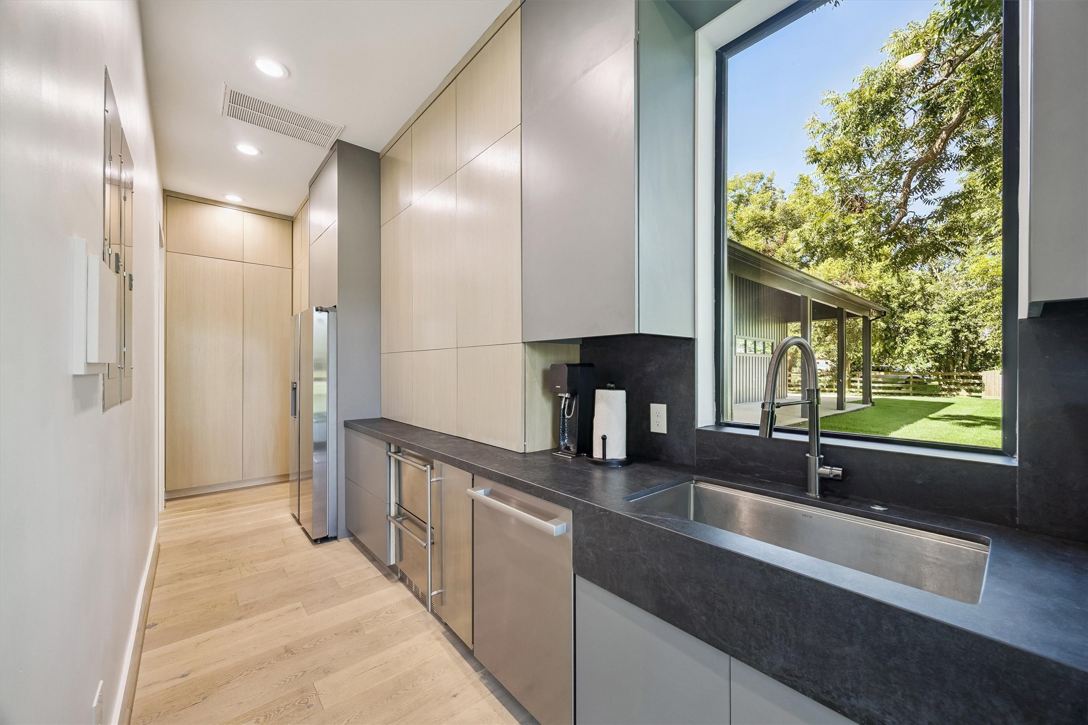 A beautifully appointed butlers pantry and secondary preparation kitchen offer generous cabinetry, expansive countertops, and a picturesque window overlooking the lush groundsproviding an elegant and functional complement to the main chefs kitchen, ideal for effortless entertaining.