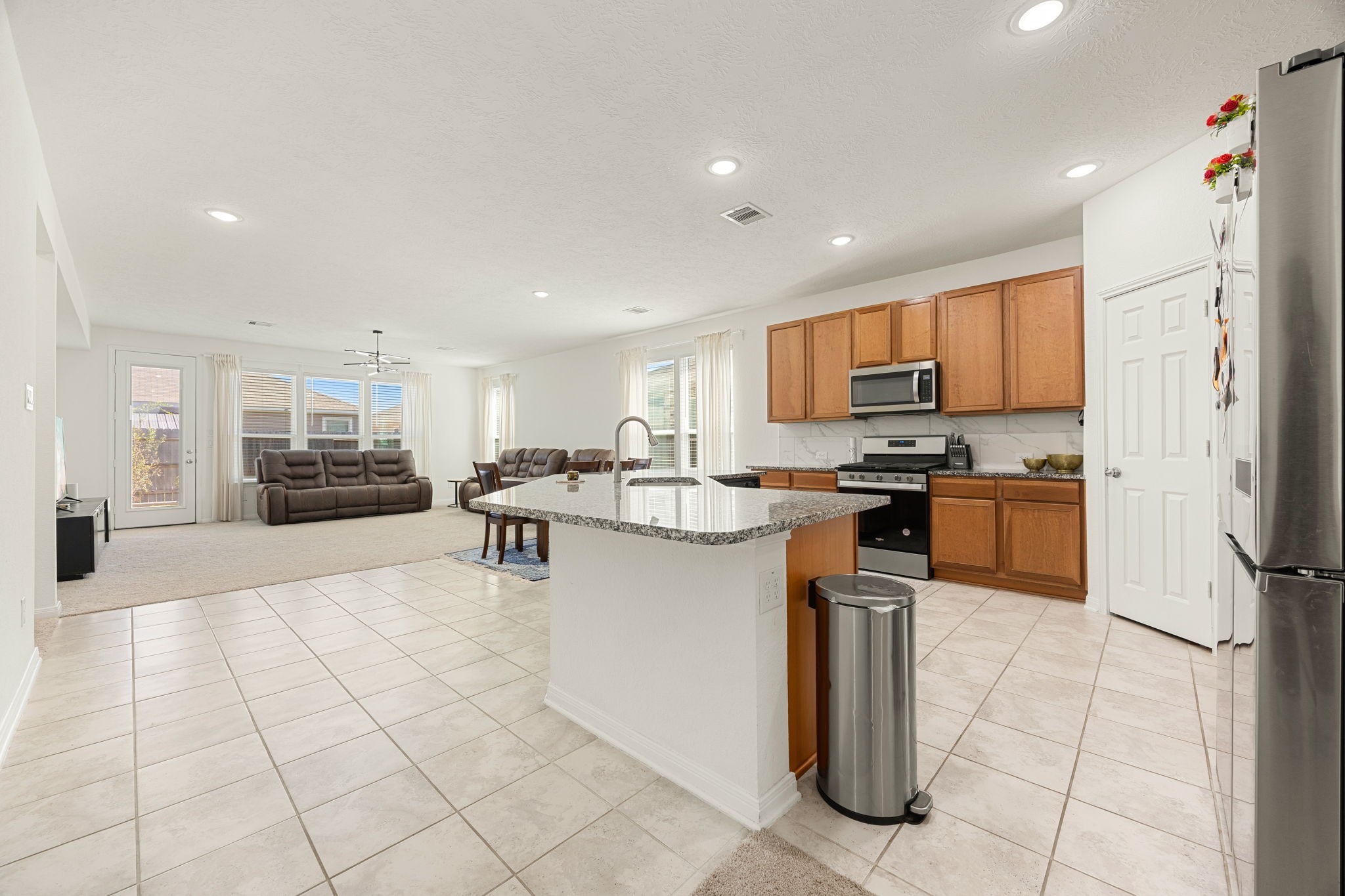 Step into the heart of the home! This stunning open-concept layout seamlessly connects the kitchen, dining, and main living areas, creating an ideal setting for everyday living and effortless entertaining. High ceilings, bright neutral tile flooring, and a flood of natural light anchor this expansive, versatile space.