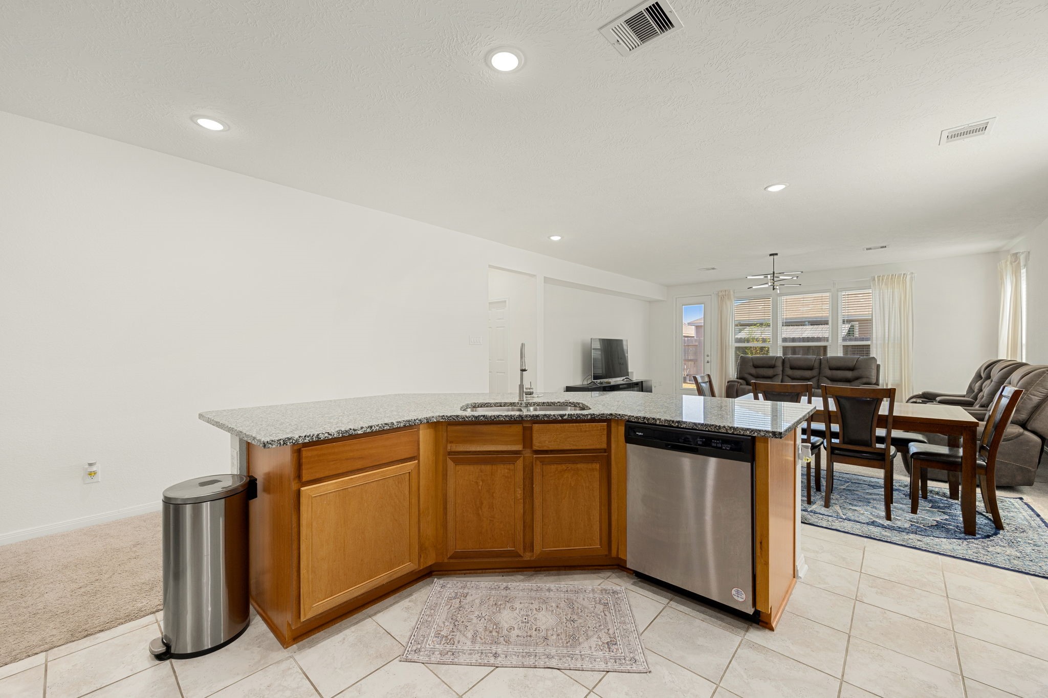 Enjoy a truly commanding perspective from the heart of the kitchen. This wide-angle view from the expansive island demonstrates how effortlessly the home chef can stay connected with guests or family, offering sweeping sightlines across the dining area, family room, and out to the sunlit backyard.